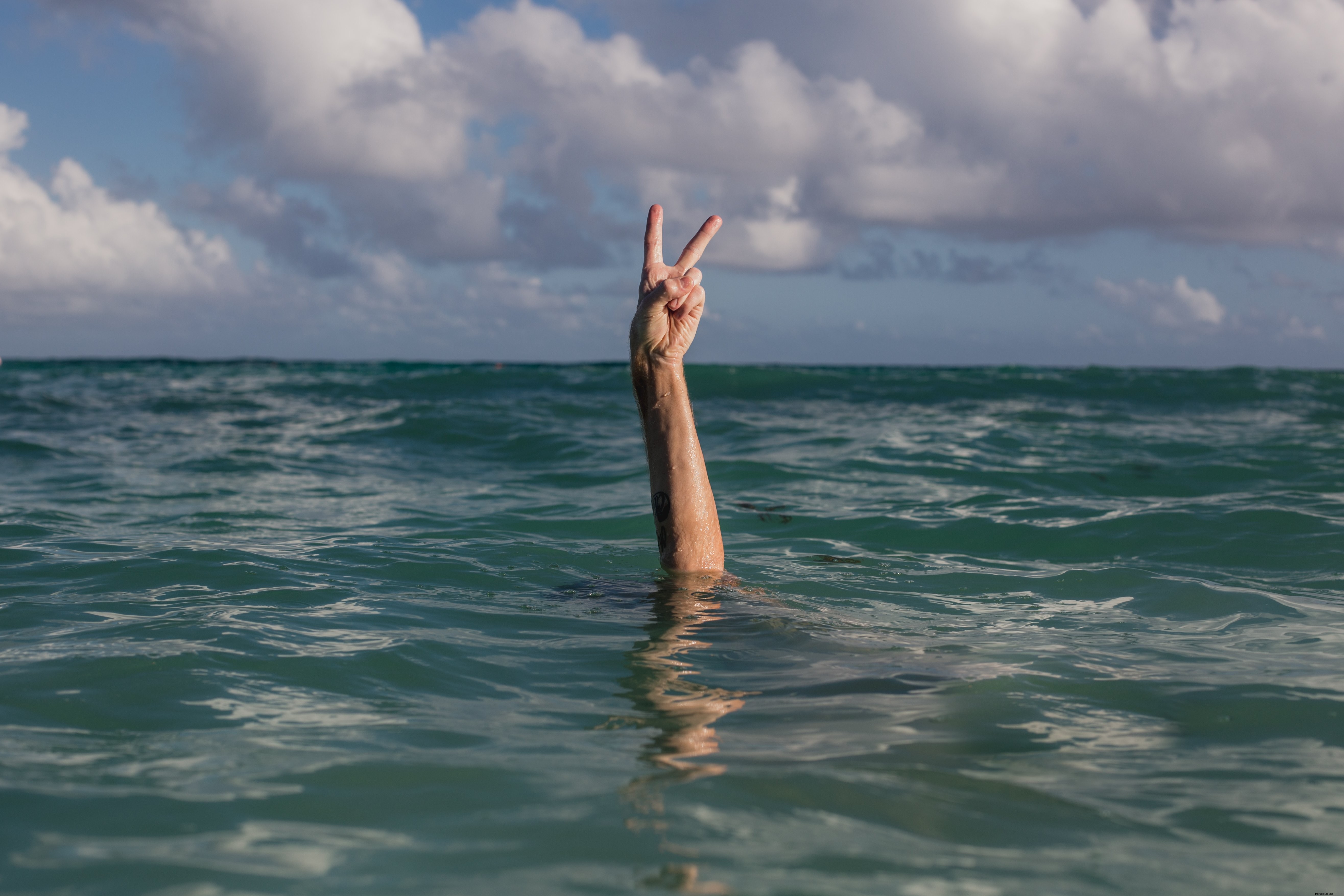 Photo de mains faisant le signe de la paix dans l eau