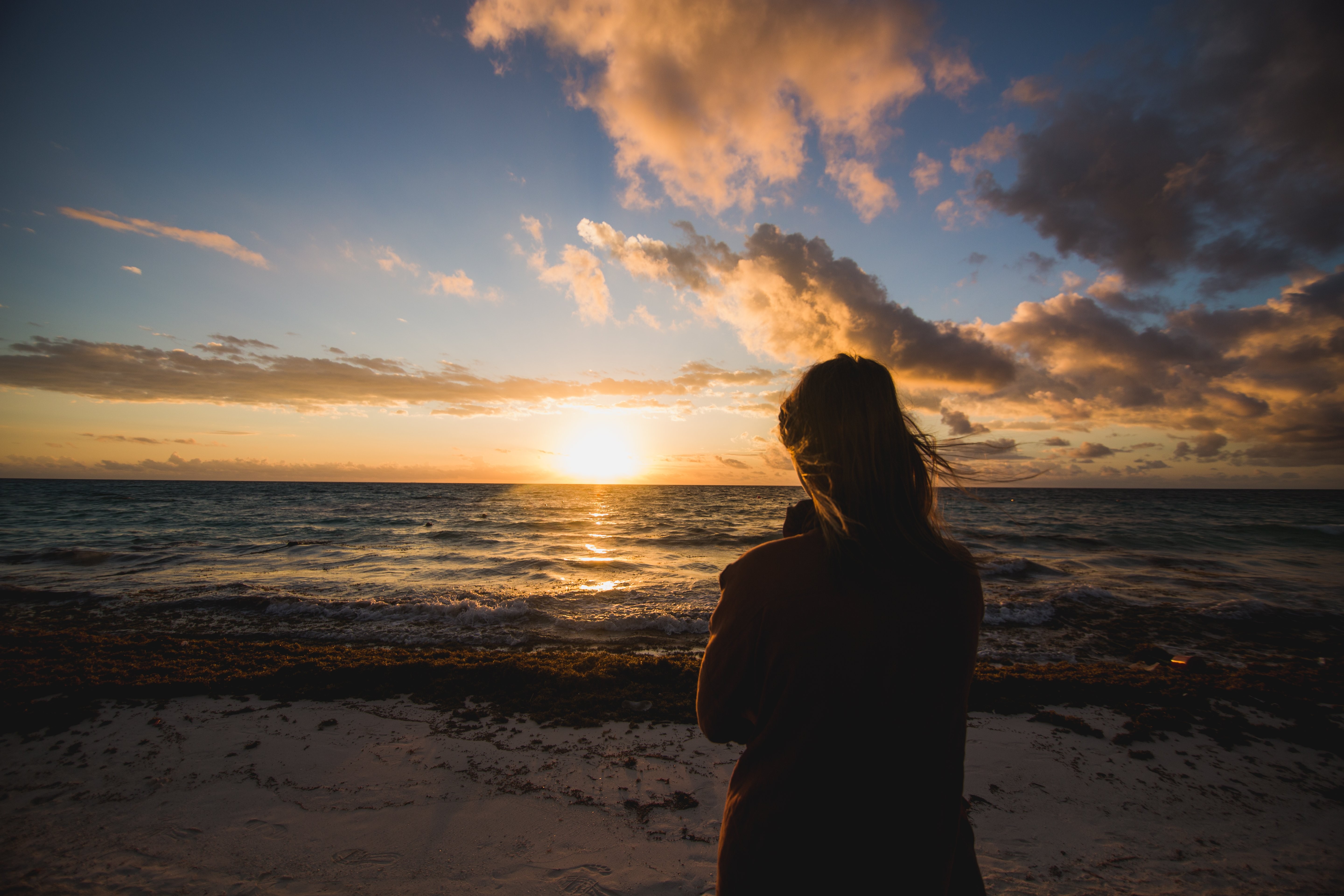 Femme admirant le lever du soleil sur la plage