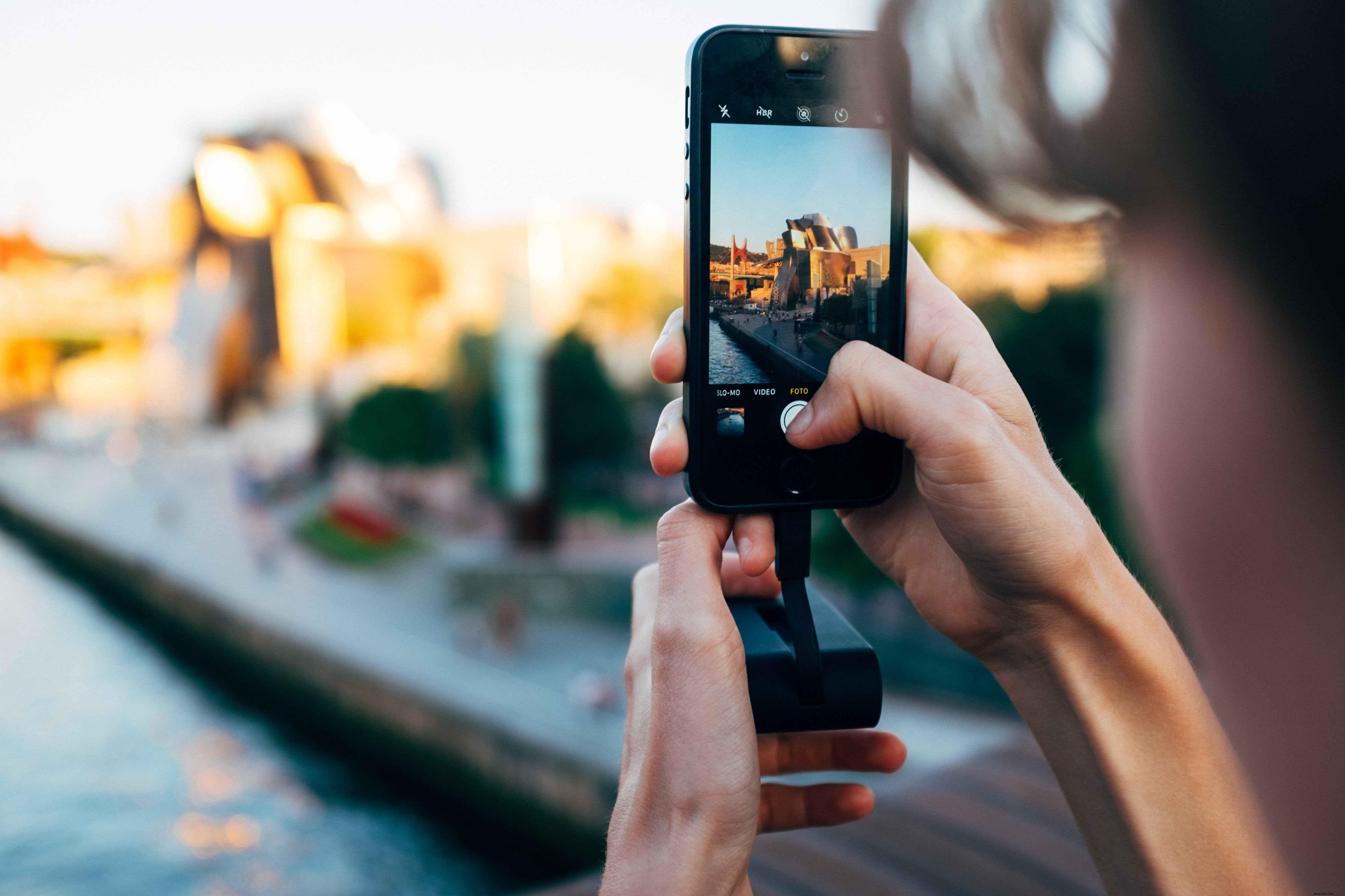 Femme photographiant un imposant bâtiment en aluminium avec son smartphone