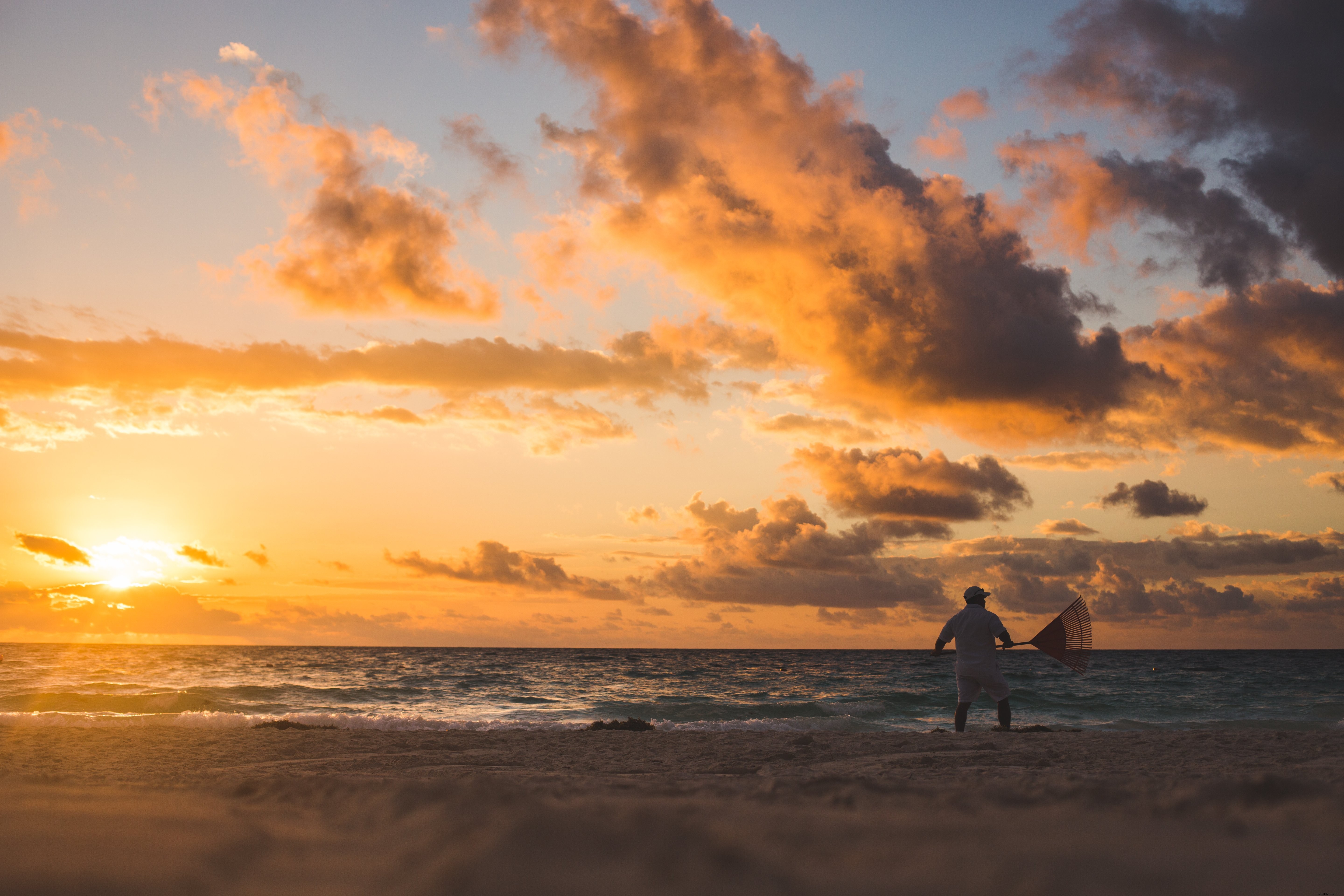 Homme ratisseur sur la plage au coucher du soleil – Photo