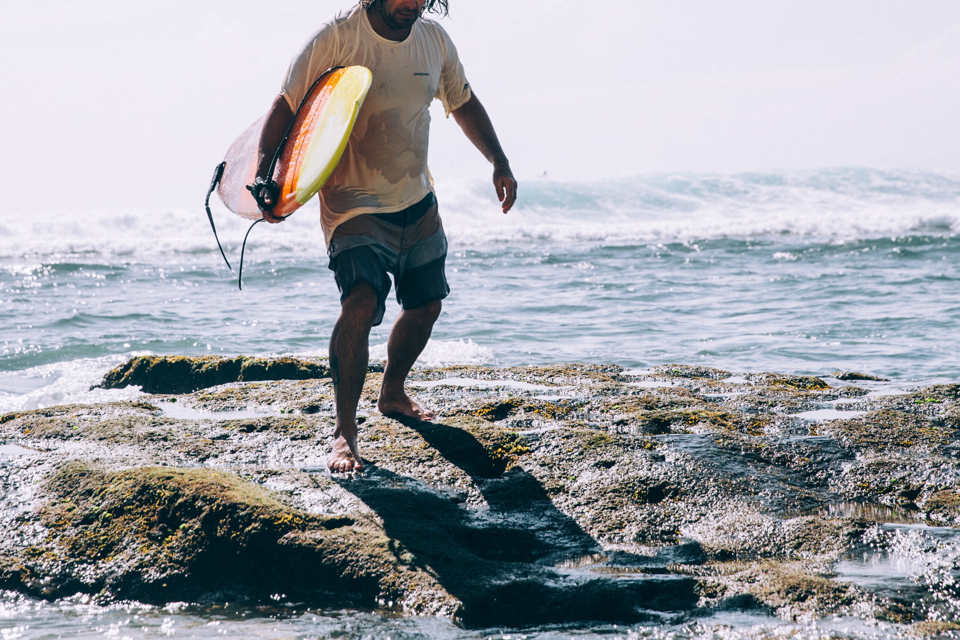 Un surfeur surgit au cœur des vagues : homme avec planche de surf