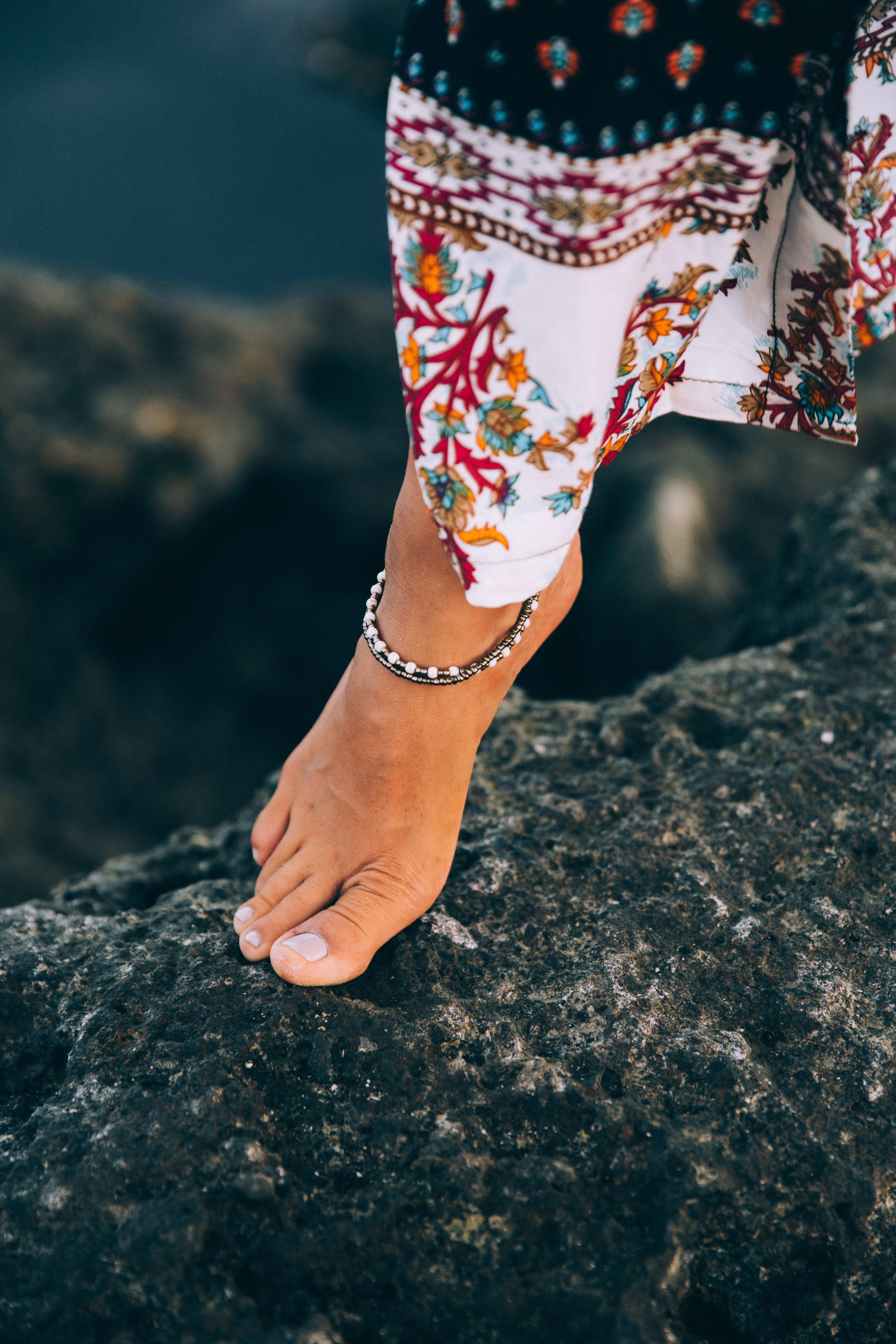 Femme bronzée exhibe son bracelet de cheville sur la plage de Rocky Seashore
