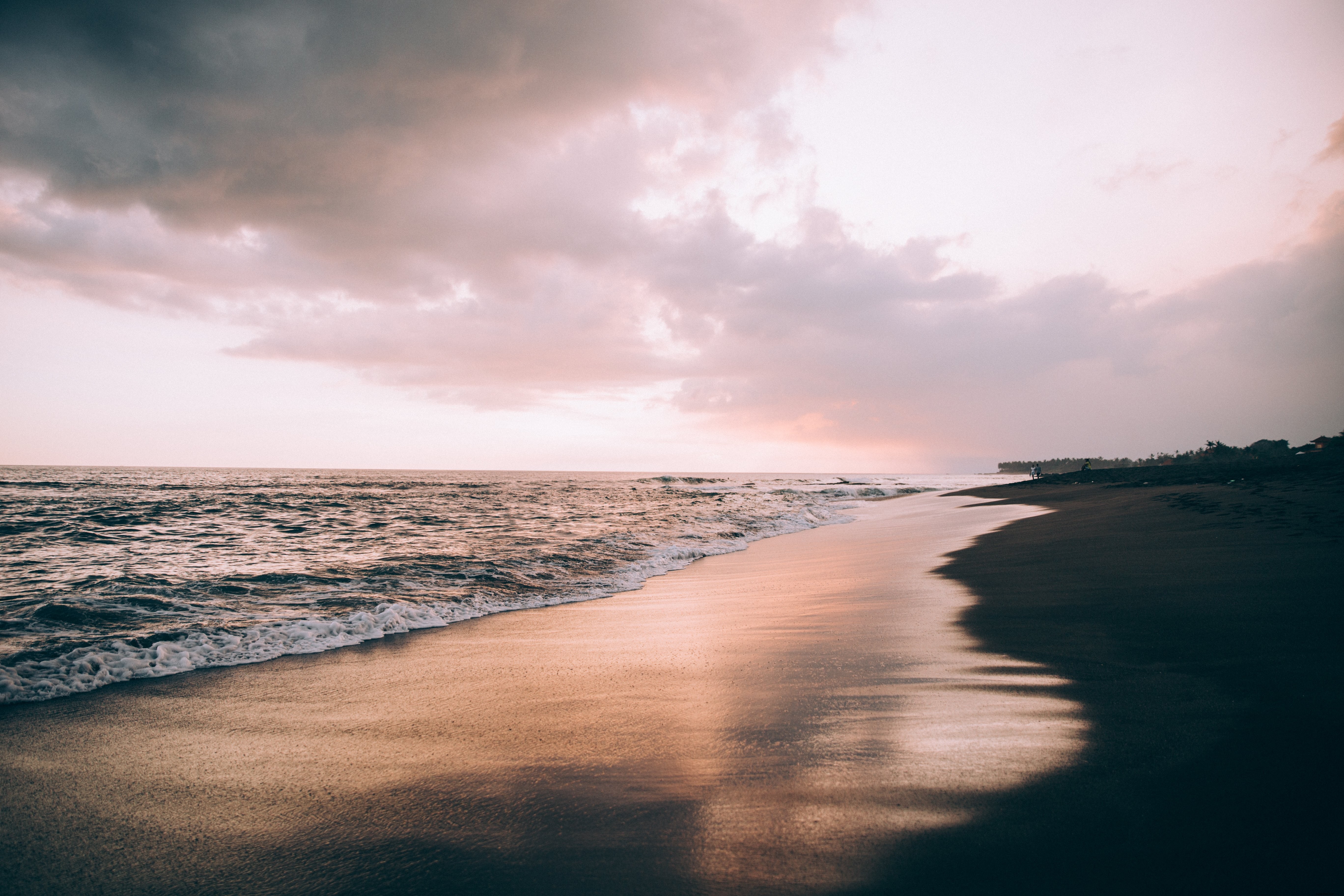 Nuages dans un ciel rose au-dessus d’une plage caressée par les vagues