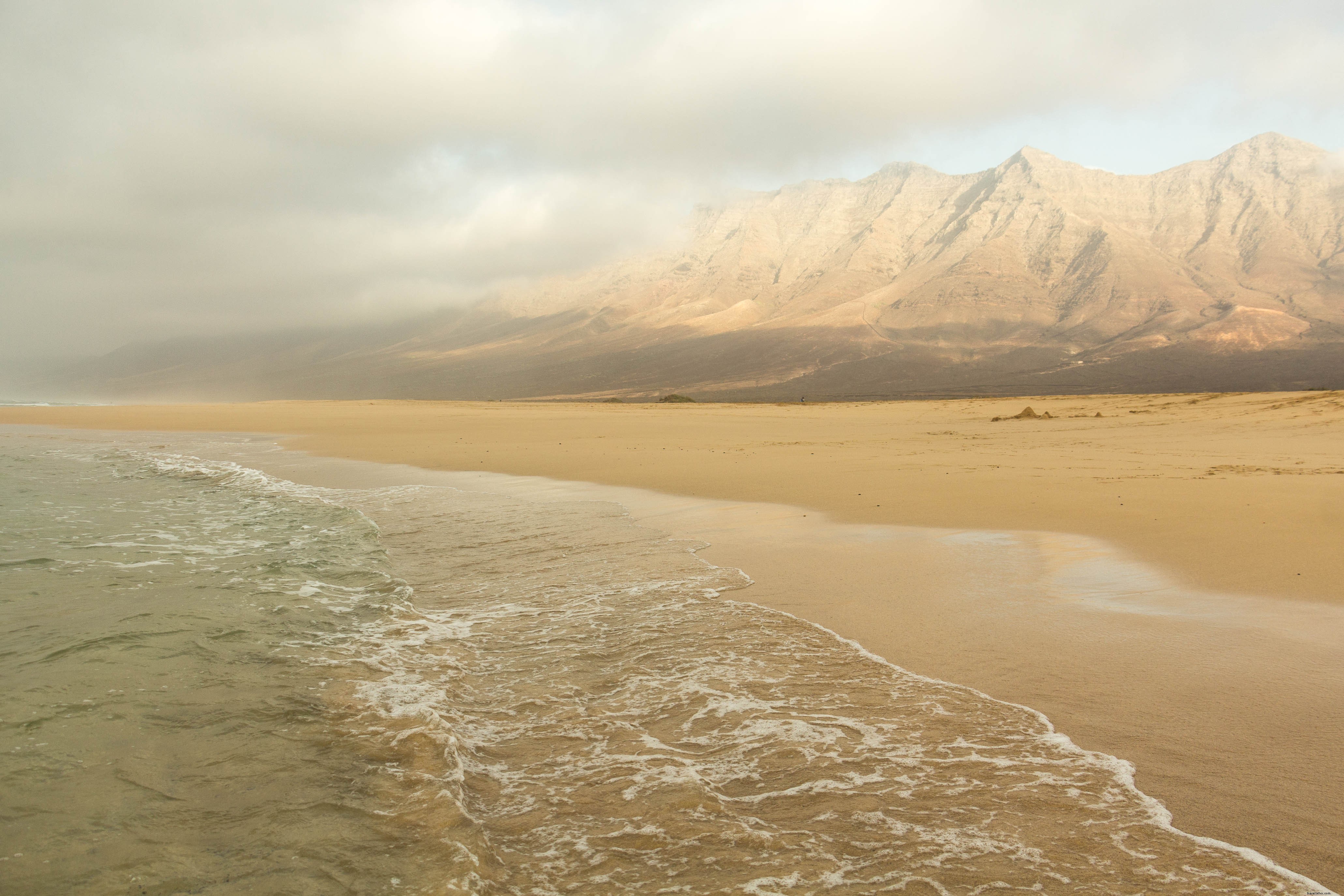 Photo de hautes montagnes surplombant l océan et la plage de sable