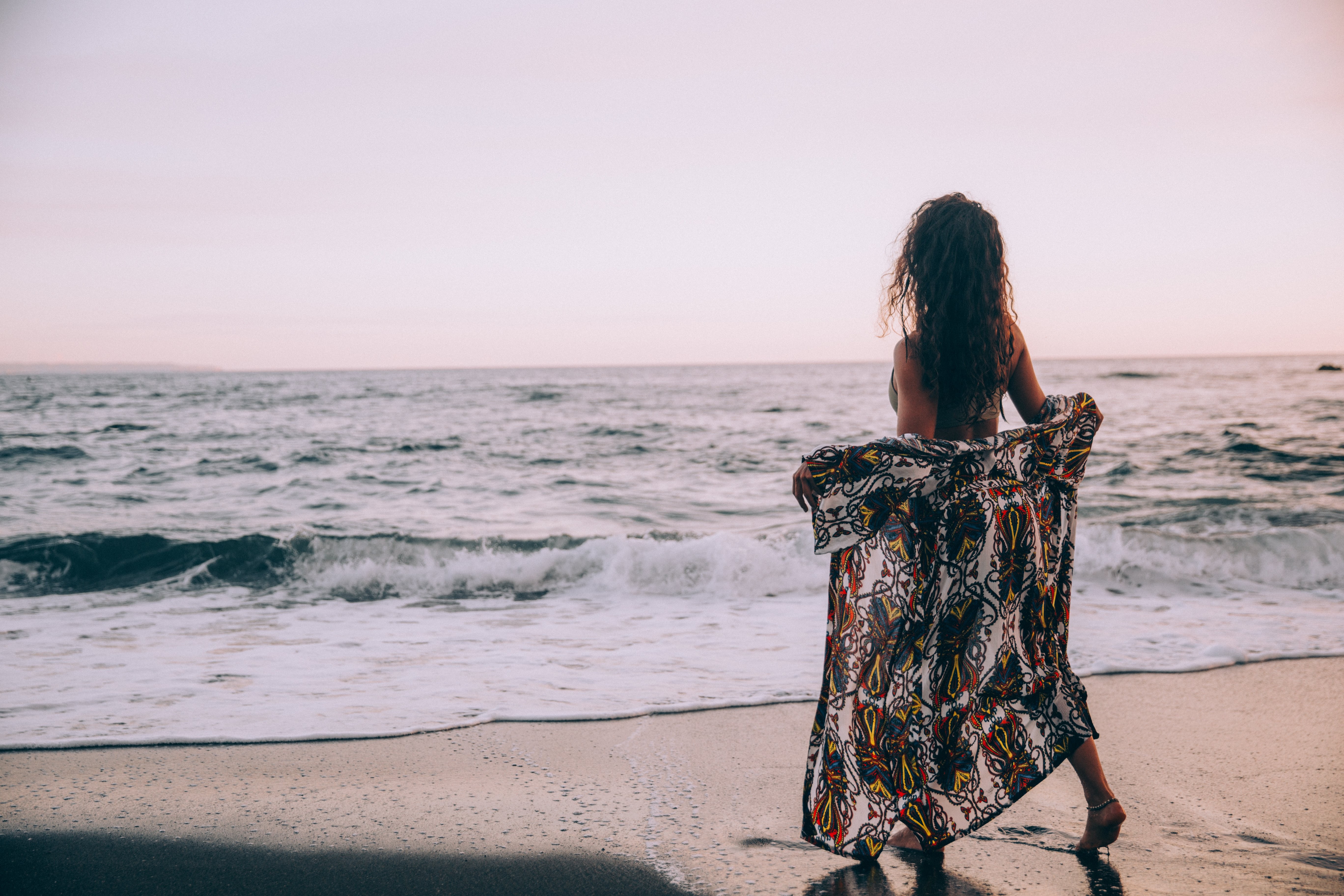 Femme sur la plage : déploiement de son paréo face aux vagues