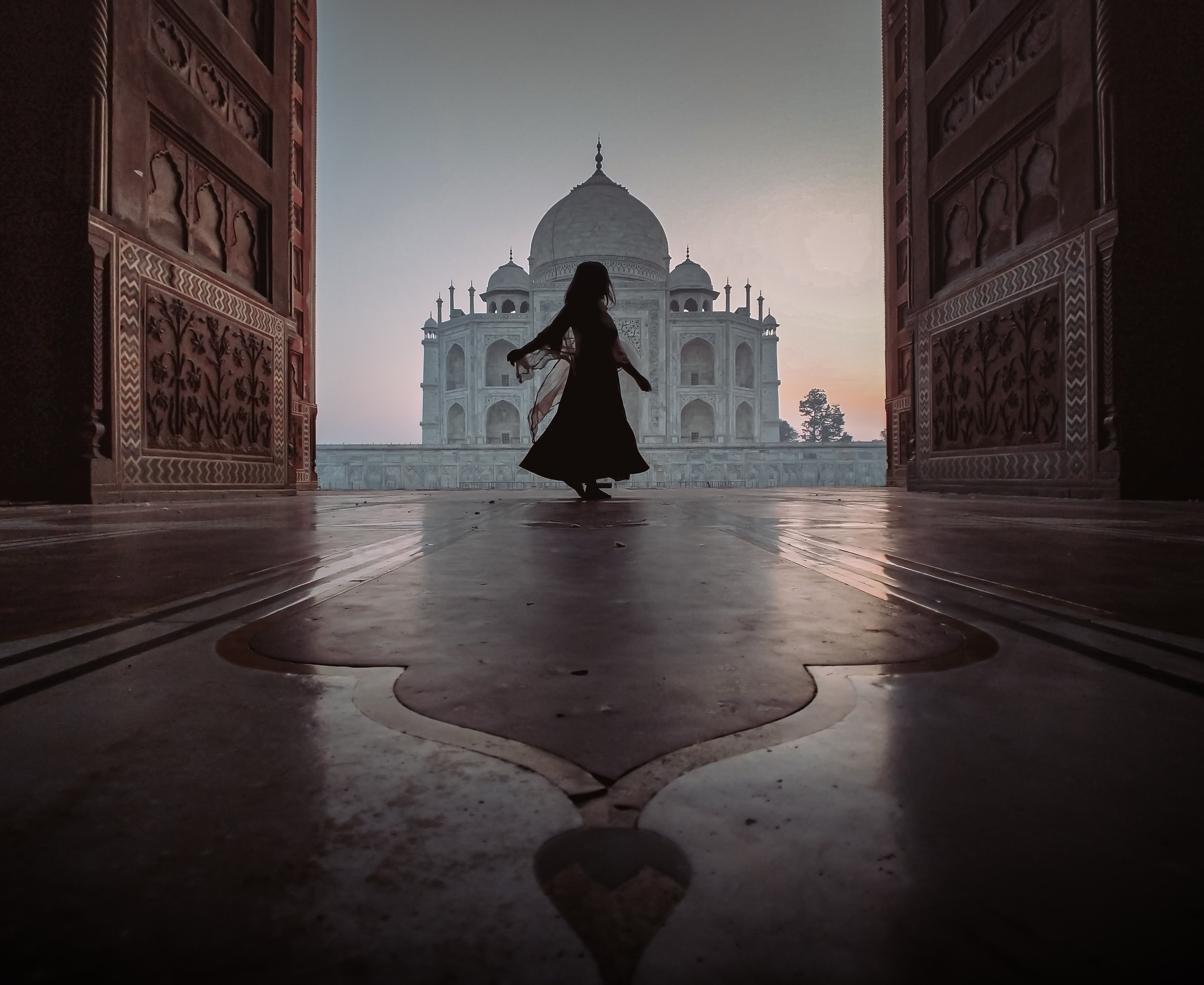 Personne dansant devant une porte avec vue sur le Taj Mahal