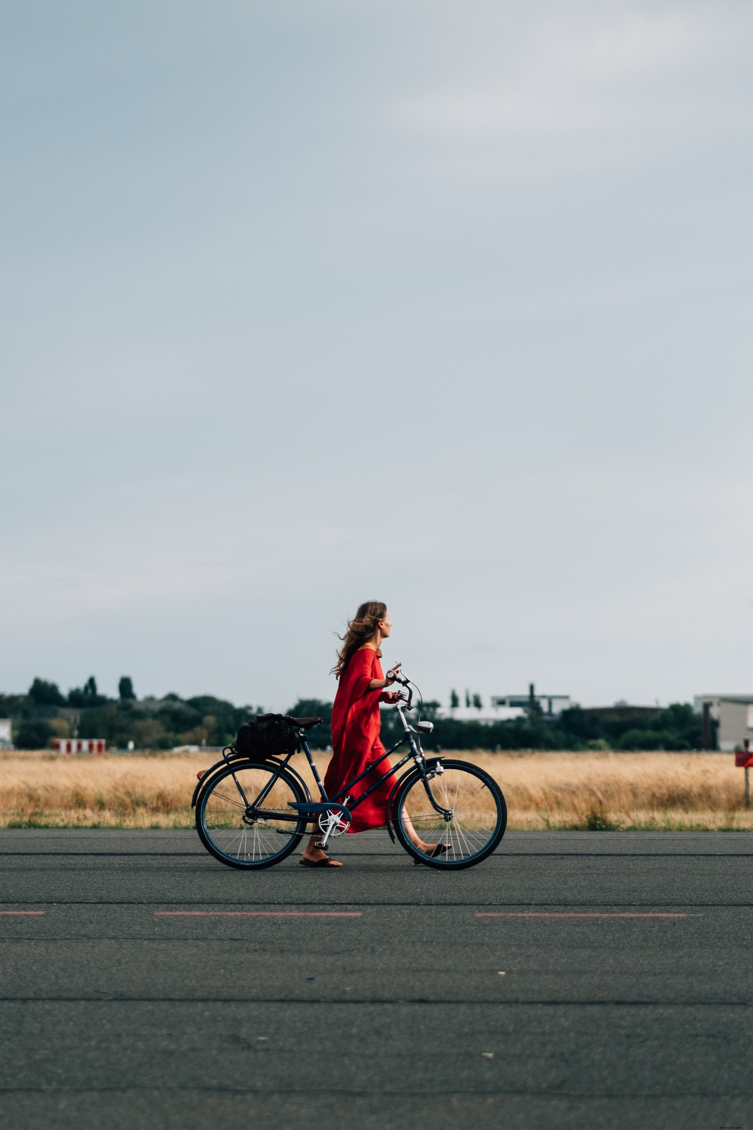 Une personne en robe rouge fait du vélo sur la route