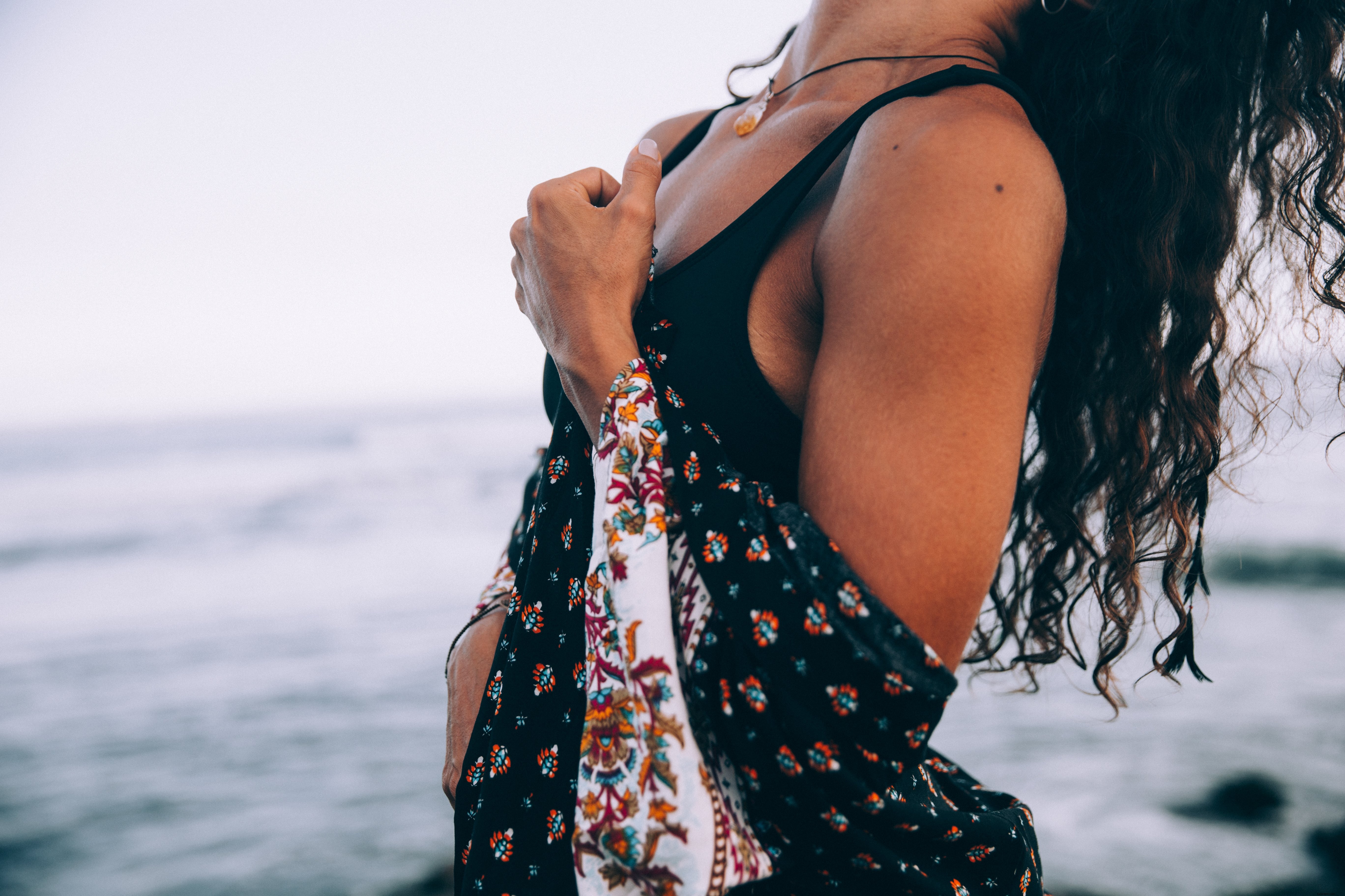 Femme en robe à motifs, la tête penchée en arrière sur la plage