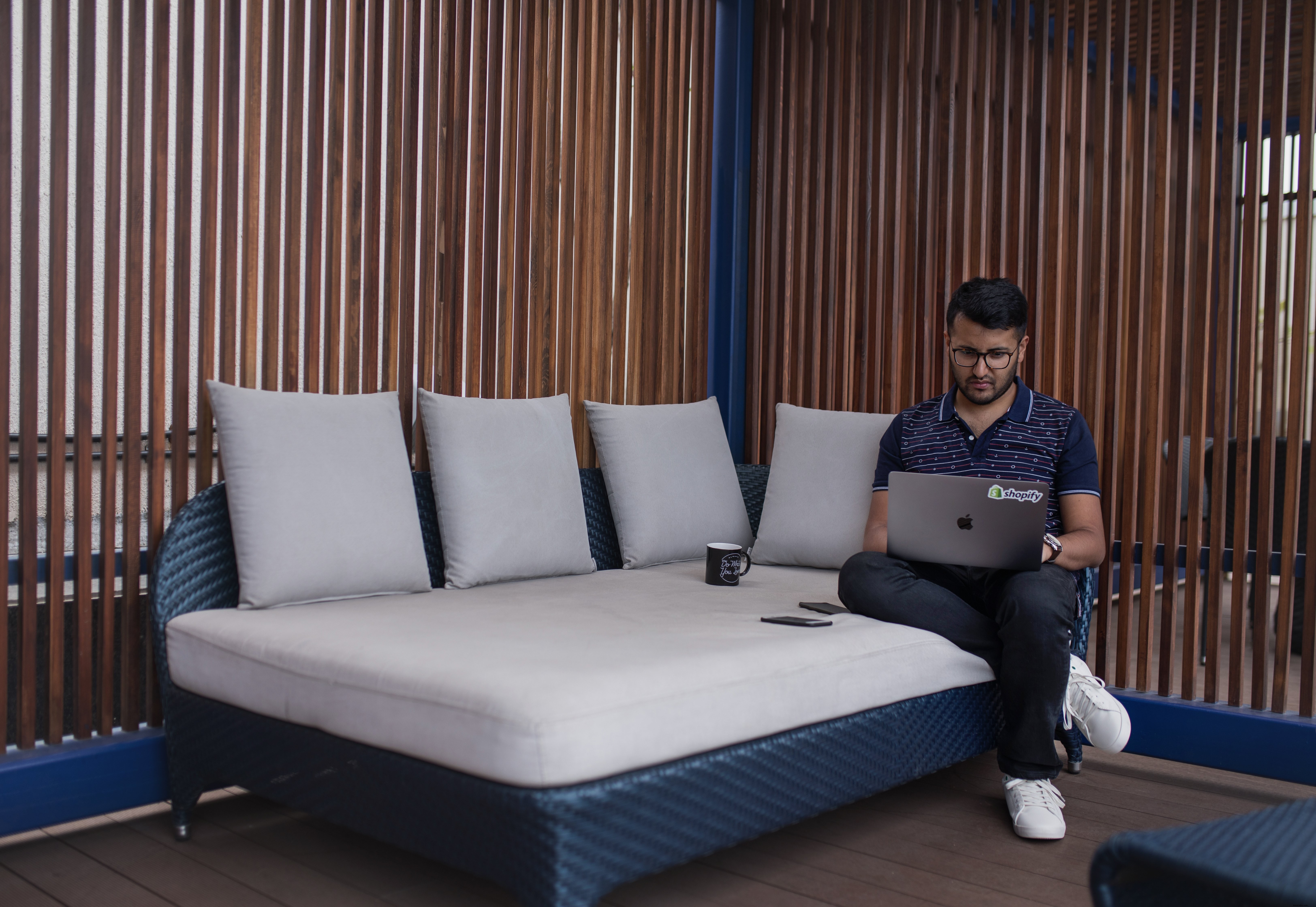 Jeune homme travaillant sur un divan de patio
