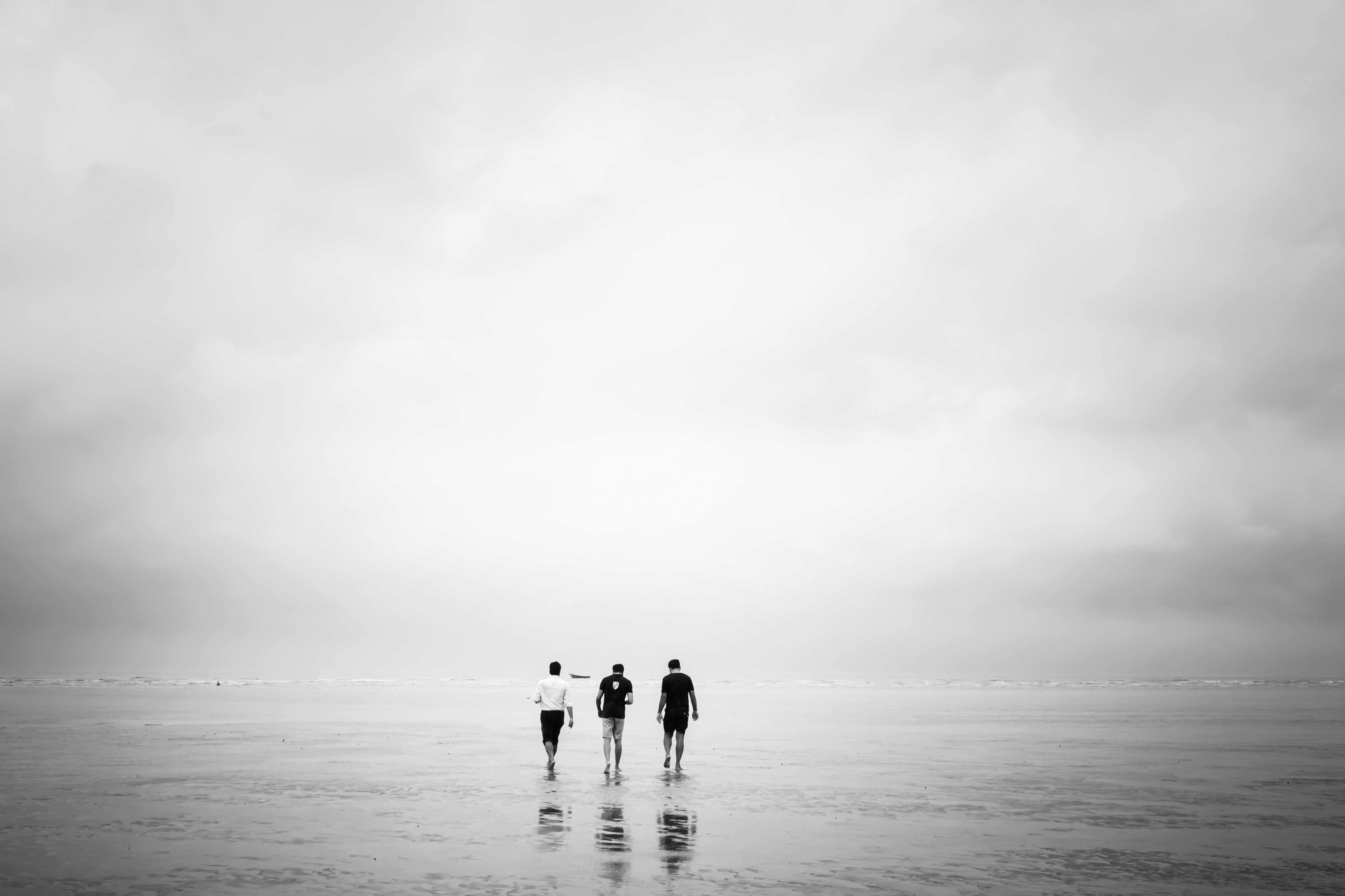 Trois hommes marchent sur une plage à marée basse
