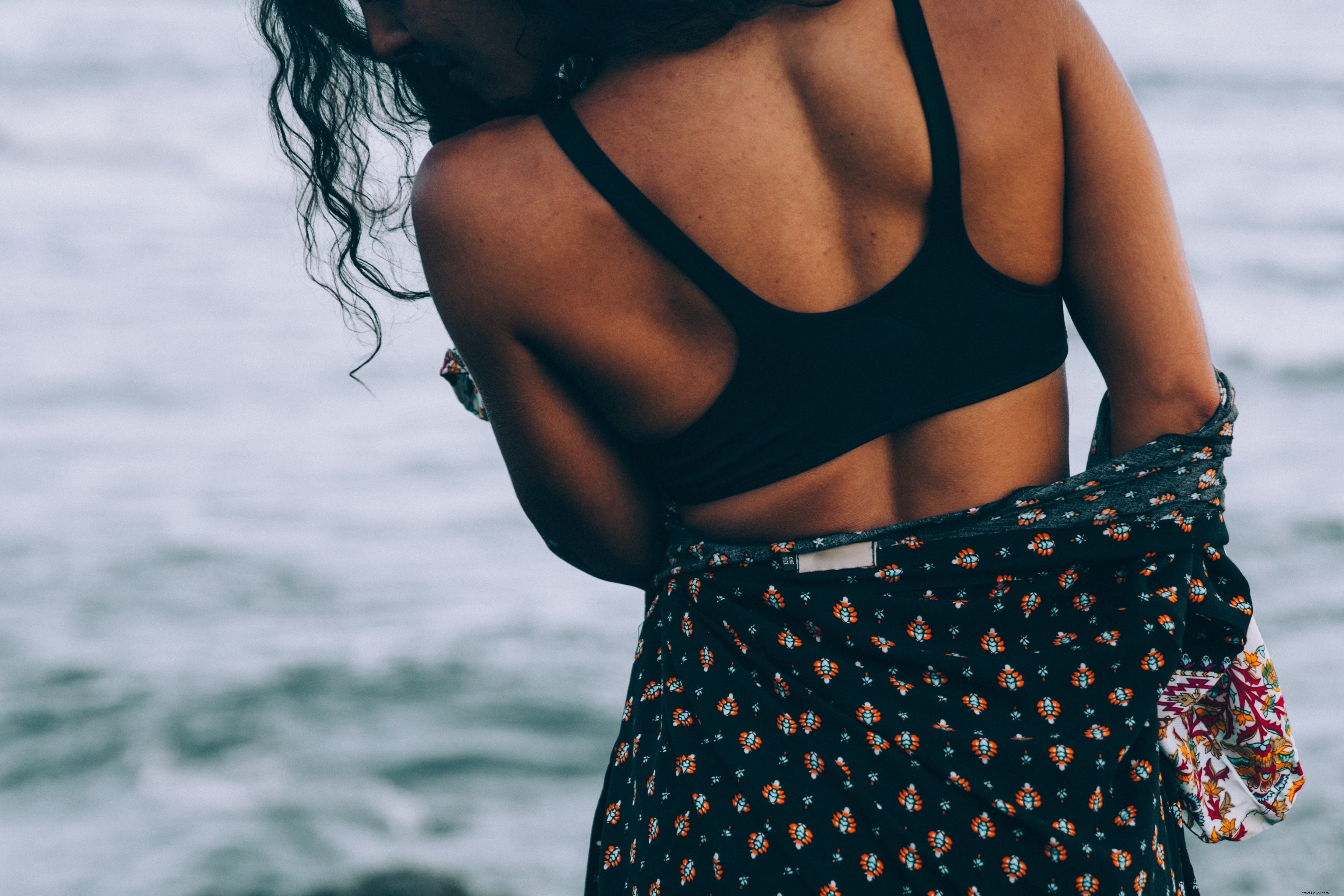 Femme bronzée en robe de plage, debout au bord de la mer
