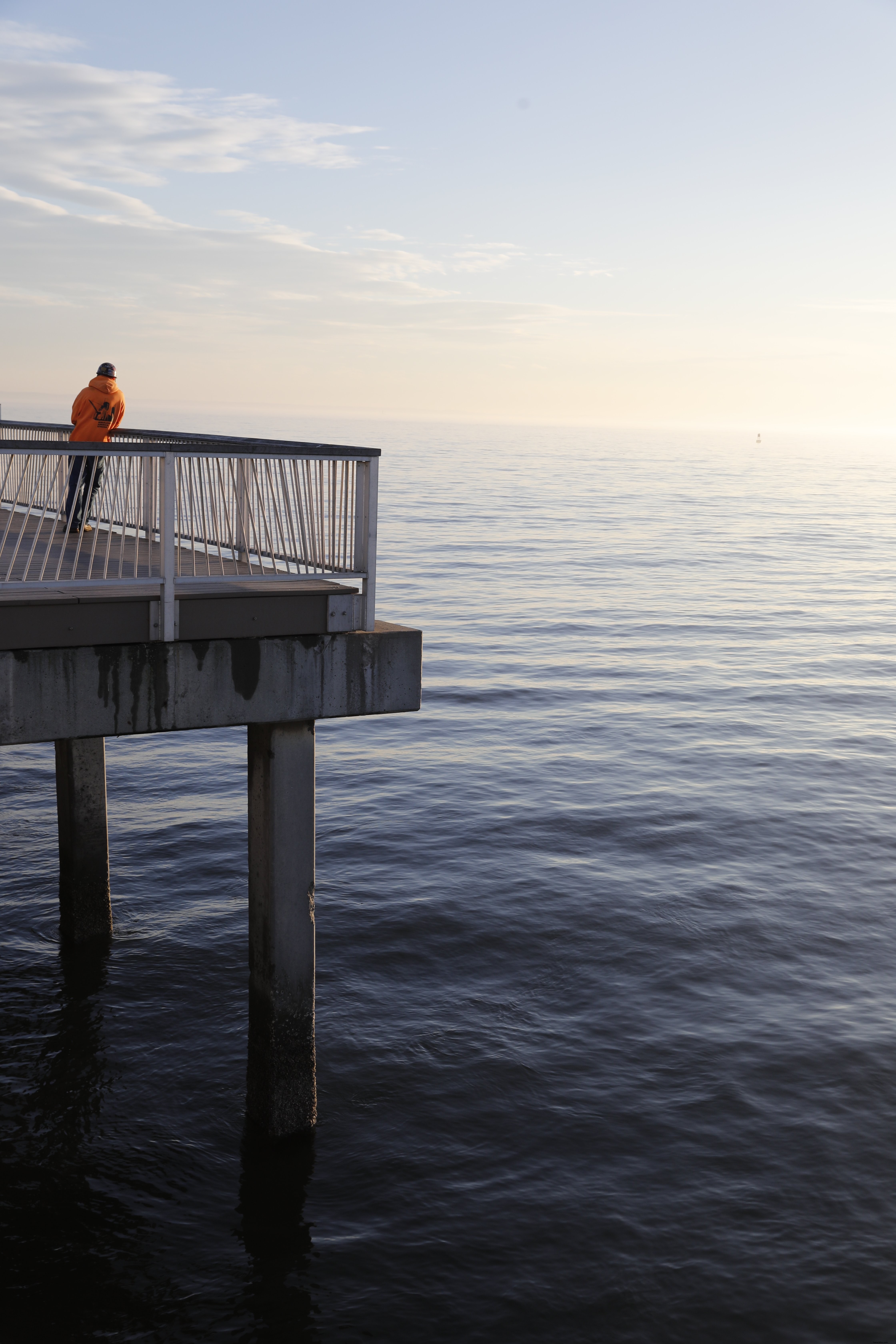 Homme solitaire debout sur une jetée au coucher du soleil