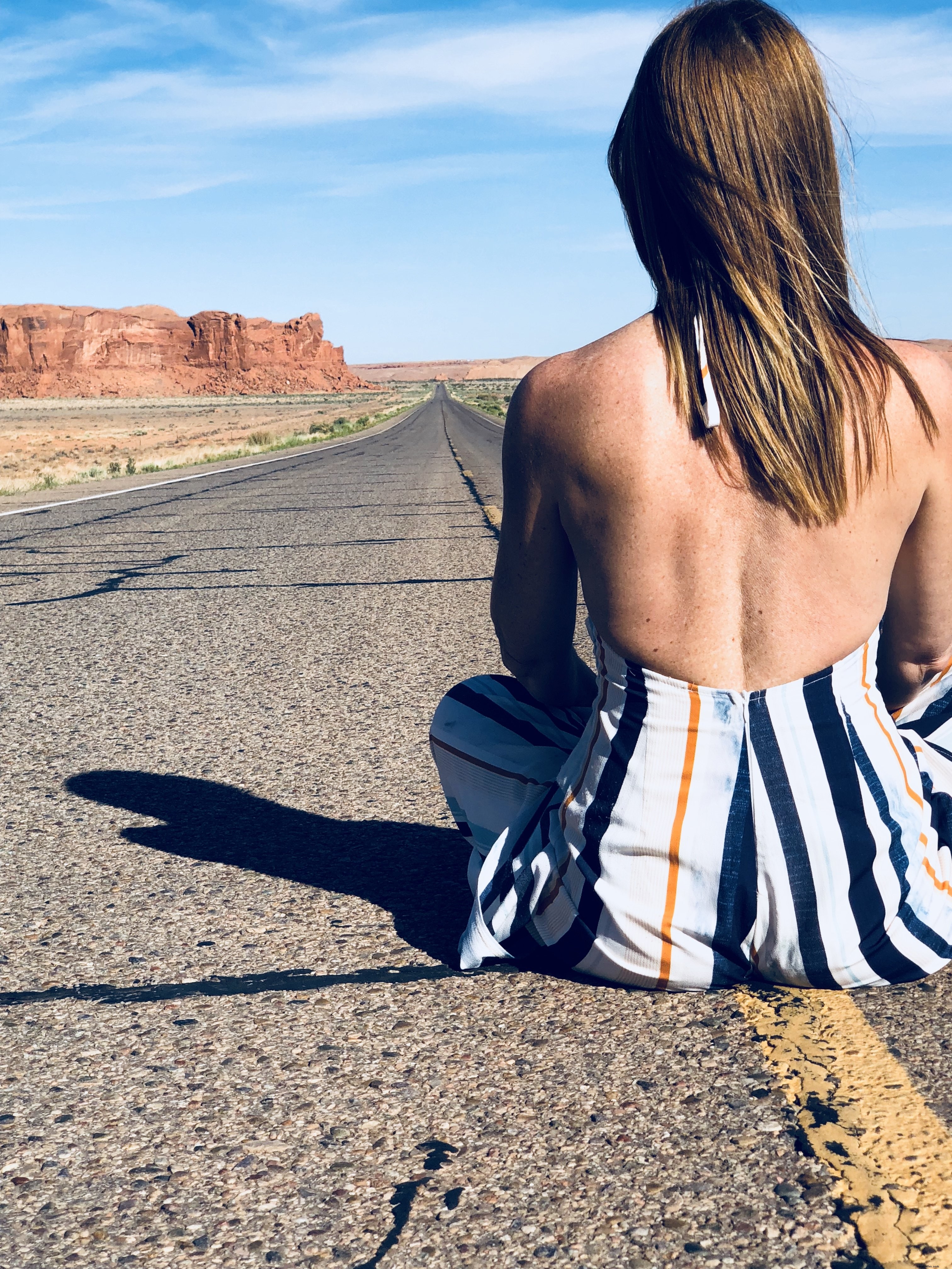 Femme assise au centre d une autoroute traversant le désert – Photo