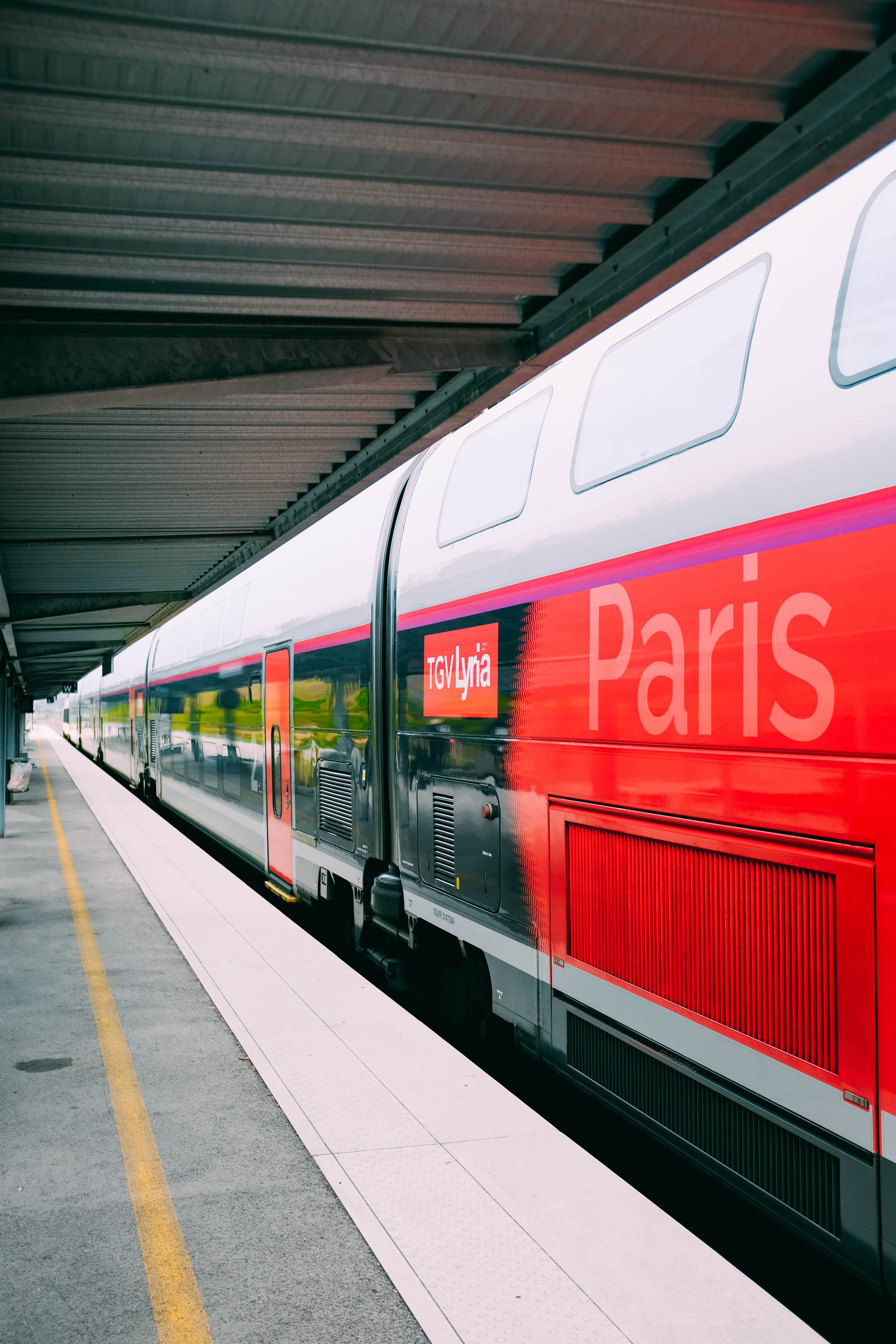 Photo d une plateforme montrant un train rouge à destination de Paris