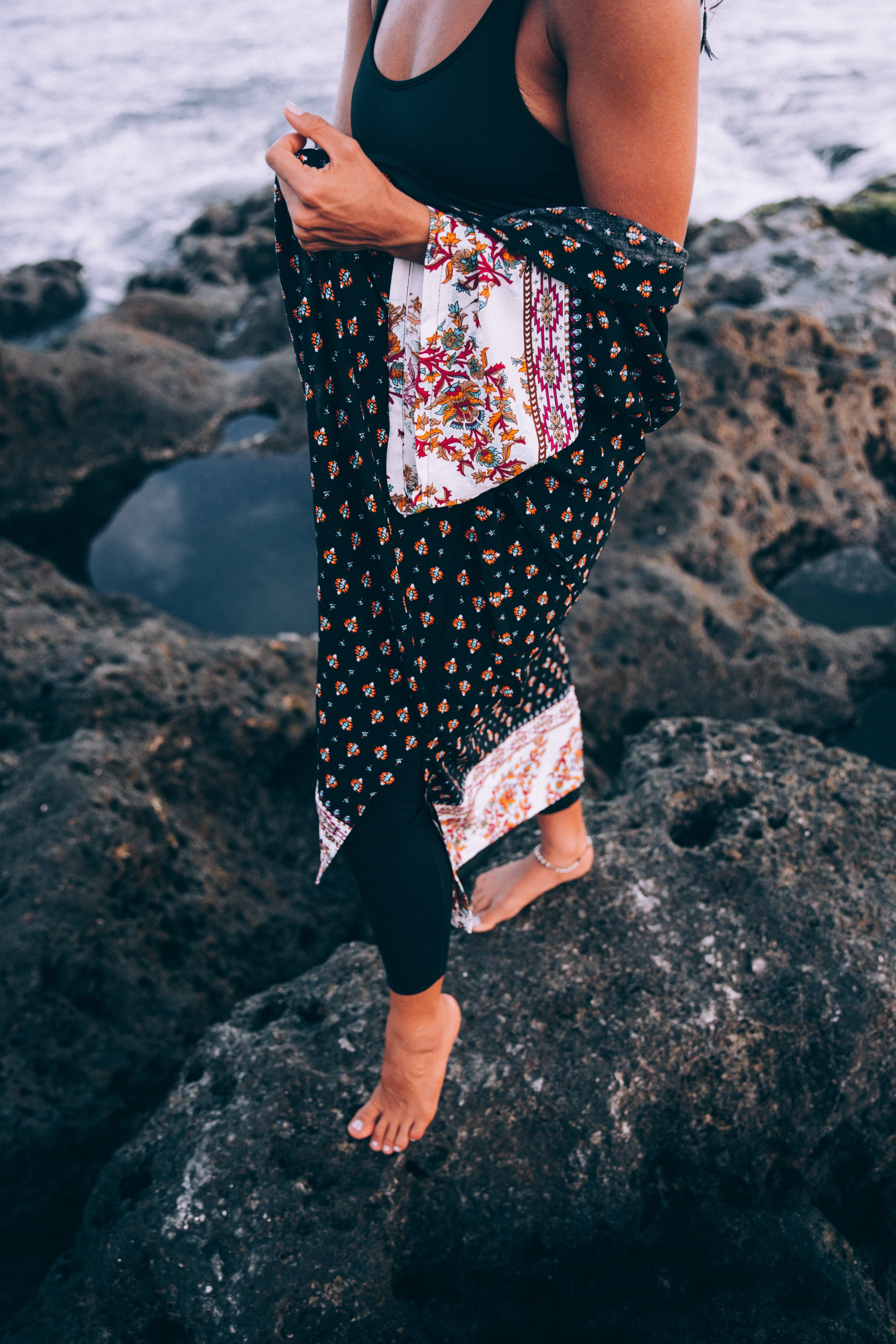 Femme bronzée drapée d’un châle à motifs, posant sur la plage