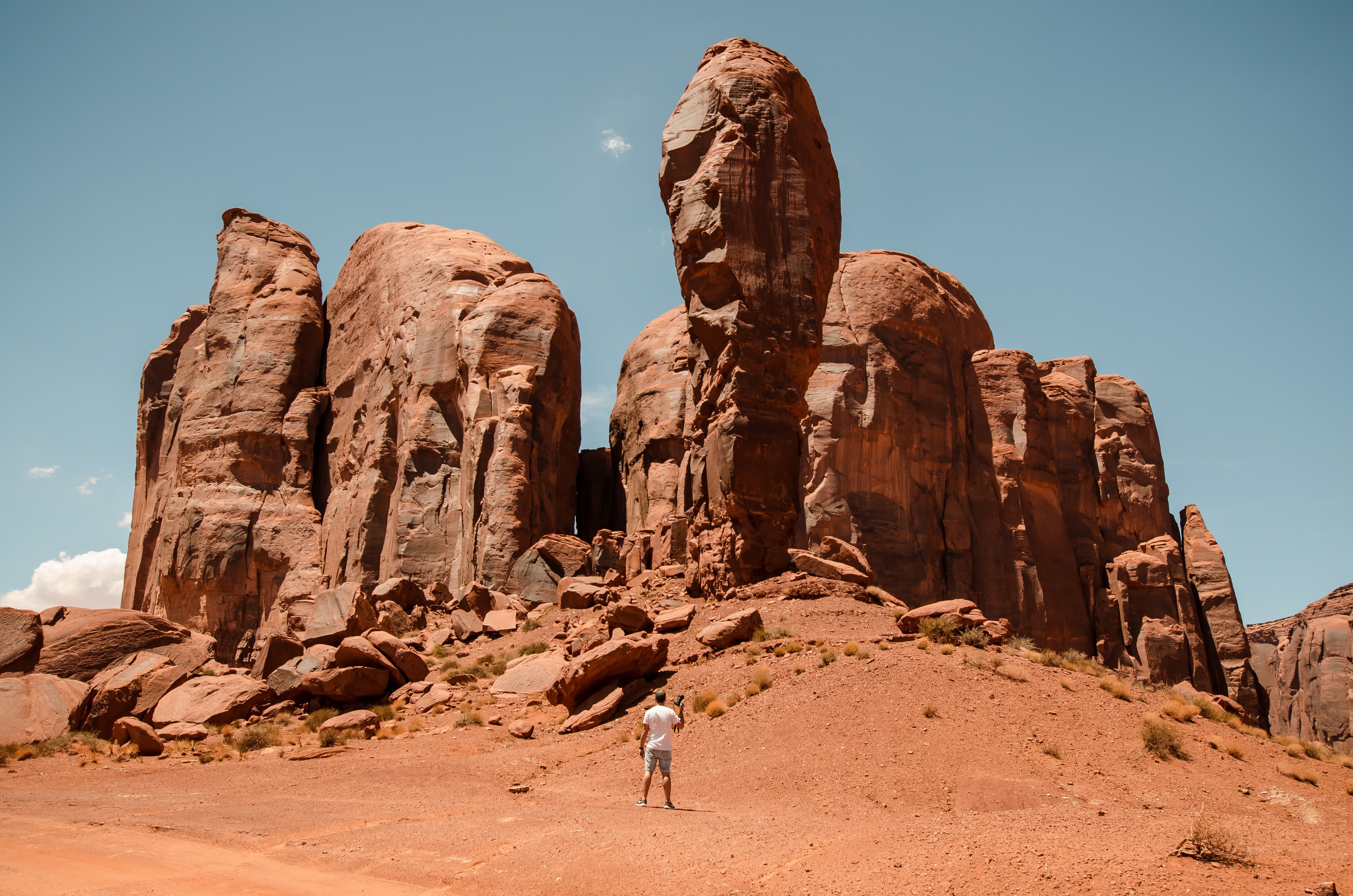 Un photographe se tient minuscule devant les imposants piliers du désert rouge