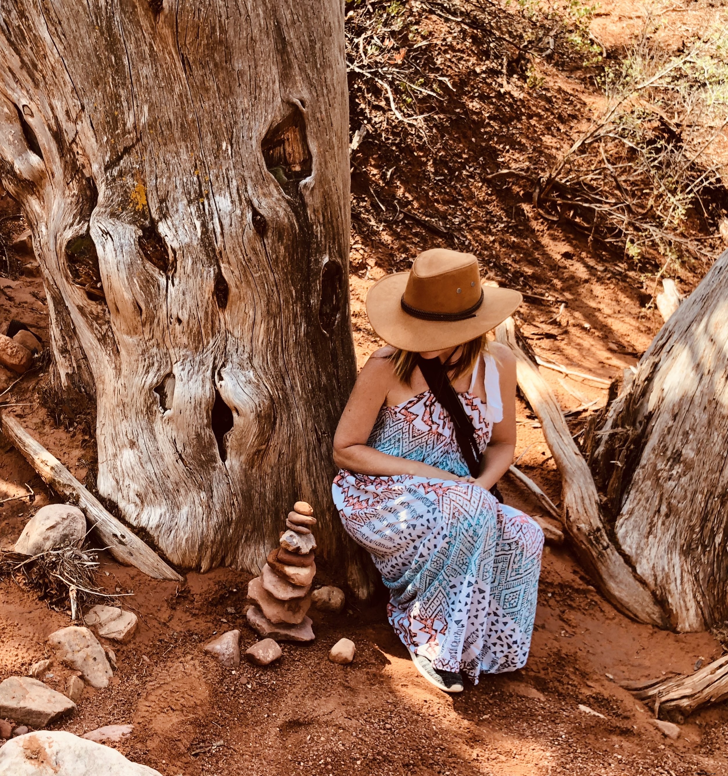 Femme en chapeau de cowboy accroupie près d’un arbre dans le désert