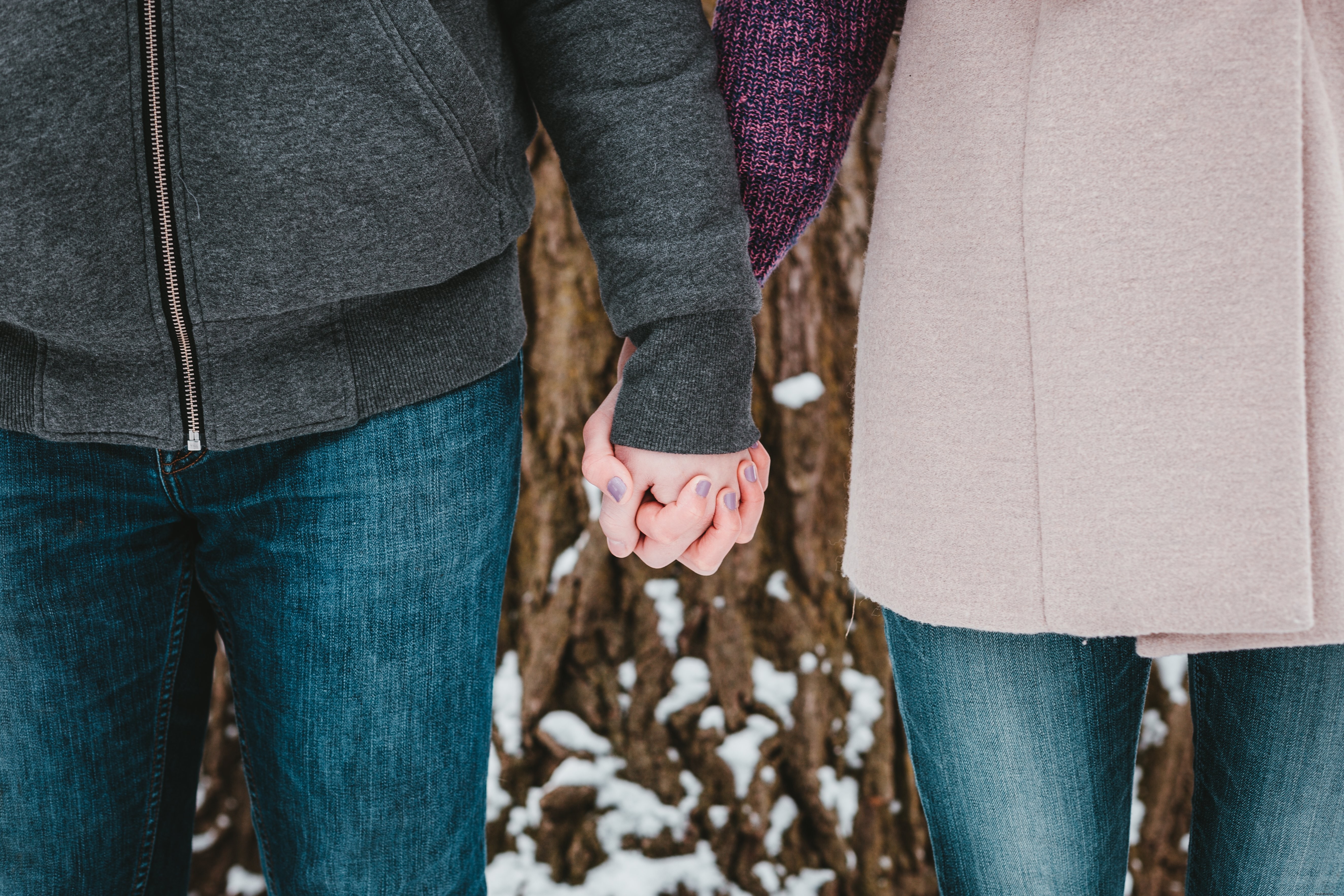 Un couple se tenant la main sous un arbre enneigé