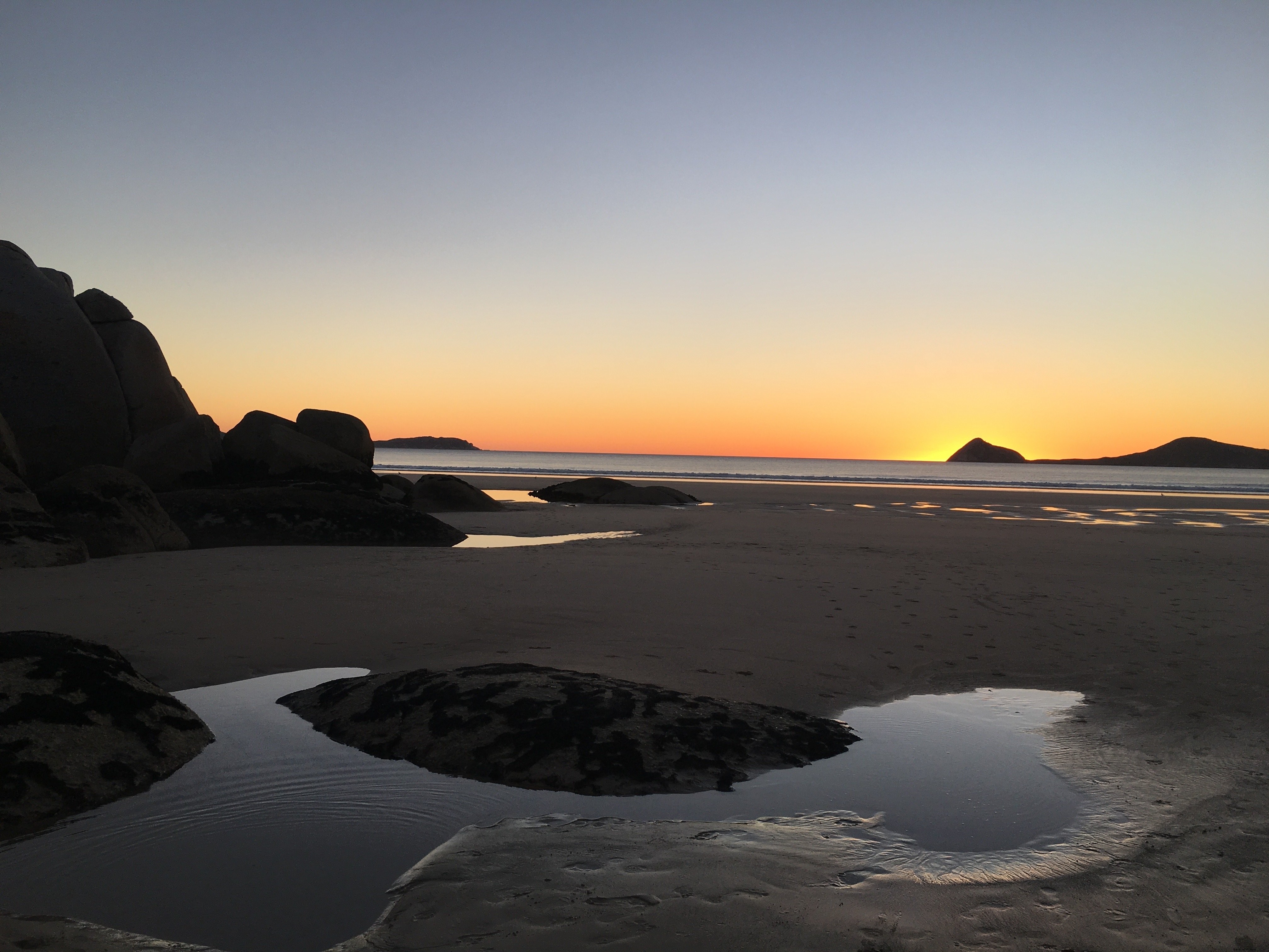 Des flaques d eau sur la plage reflètent le coucher du soleil