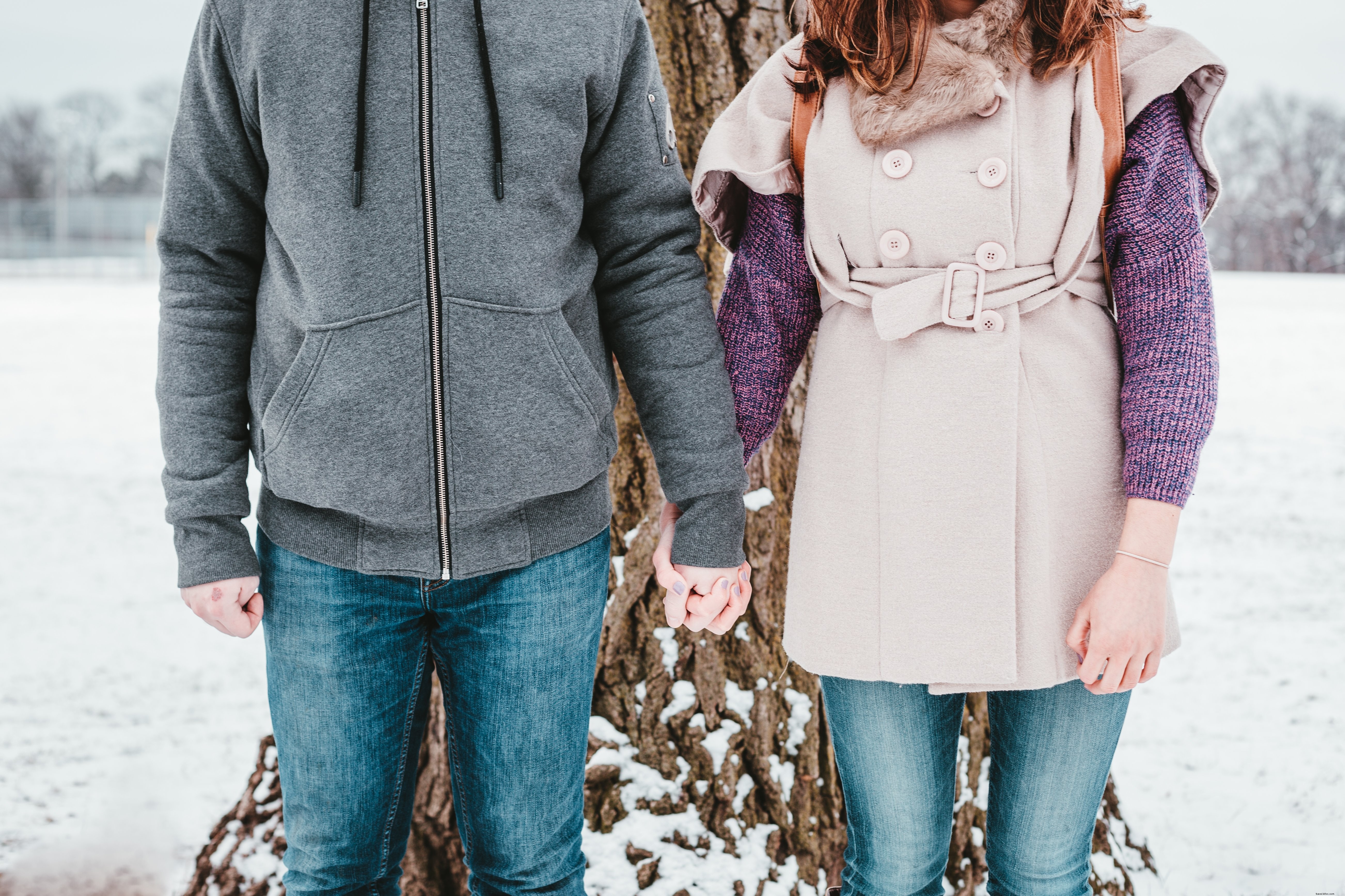 Un couple brave l hiver devant un grand arbre