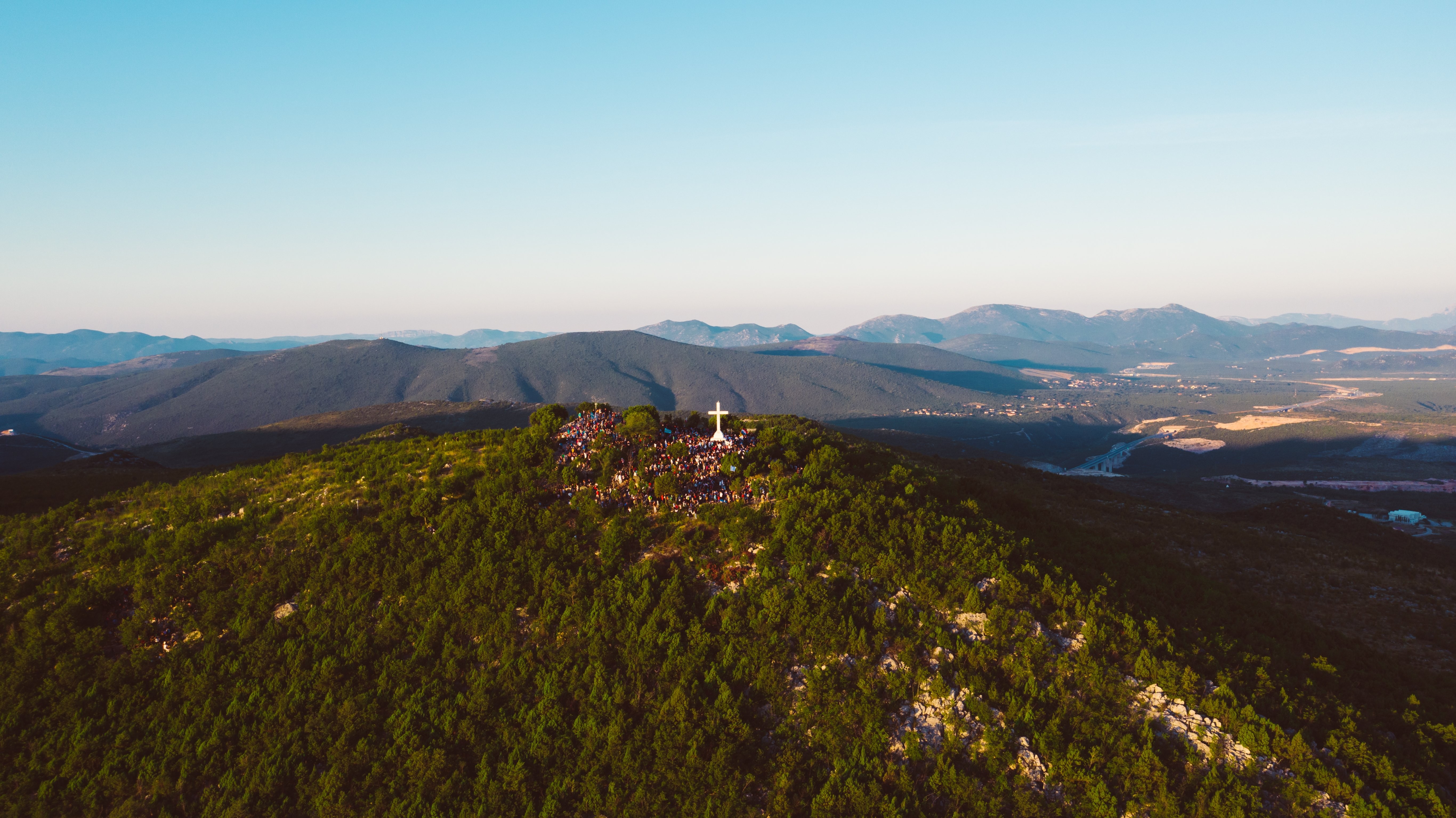 Des touristes admirent une imposante croix au sommet d’une montagne