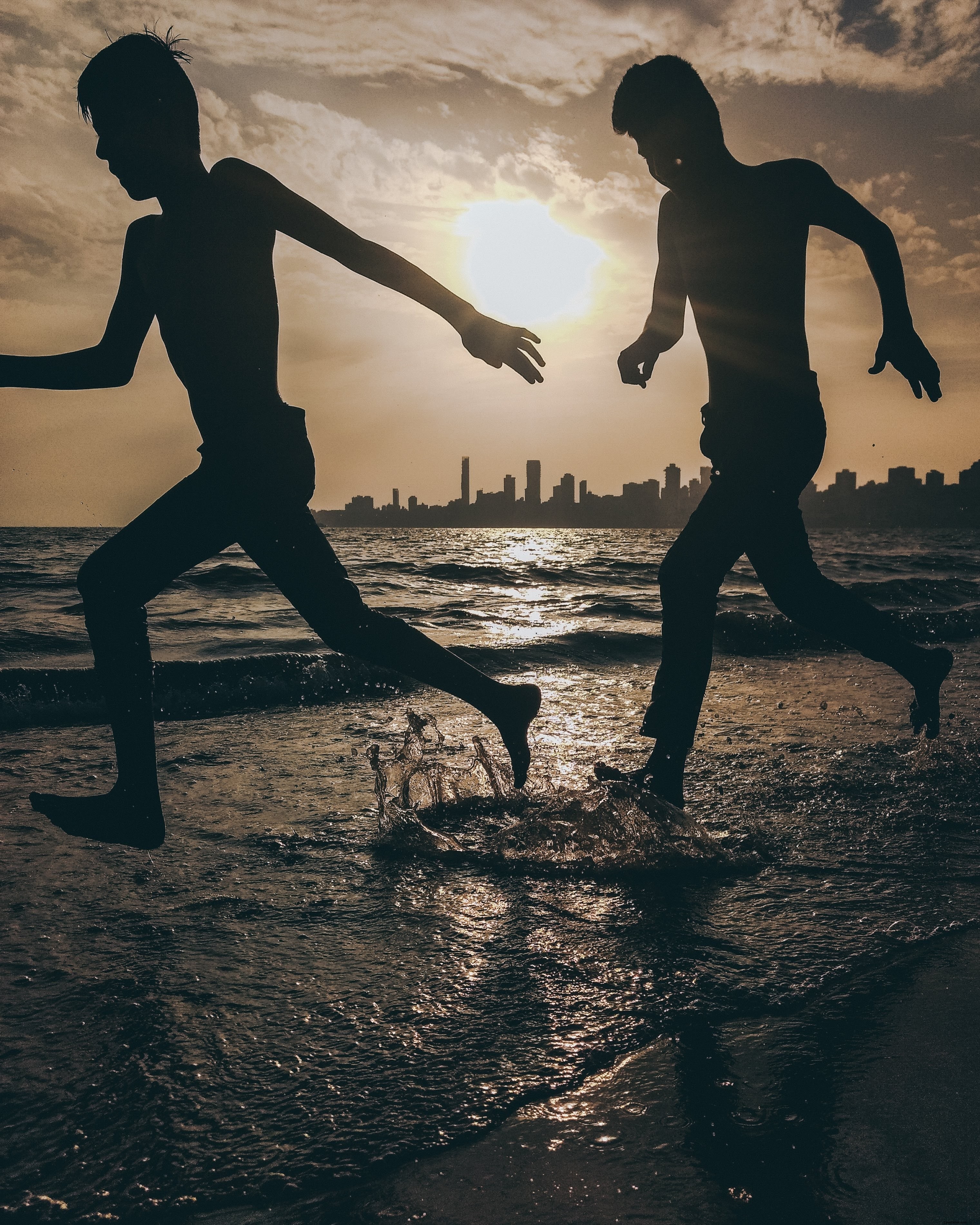 Photo de deux silhouettes éclaboussant sur la plage