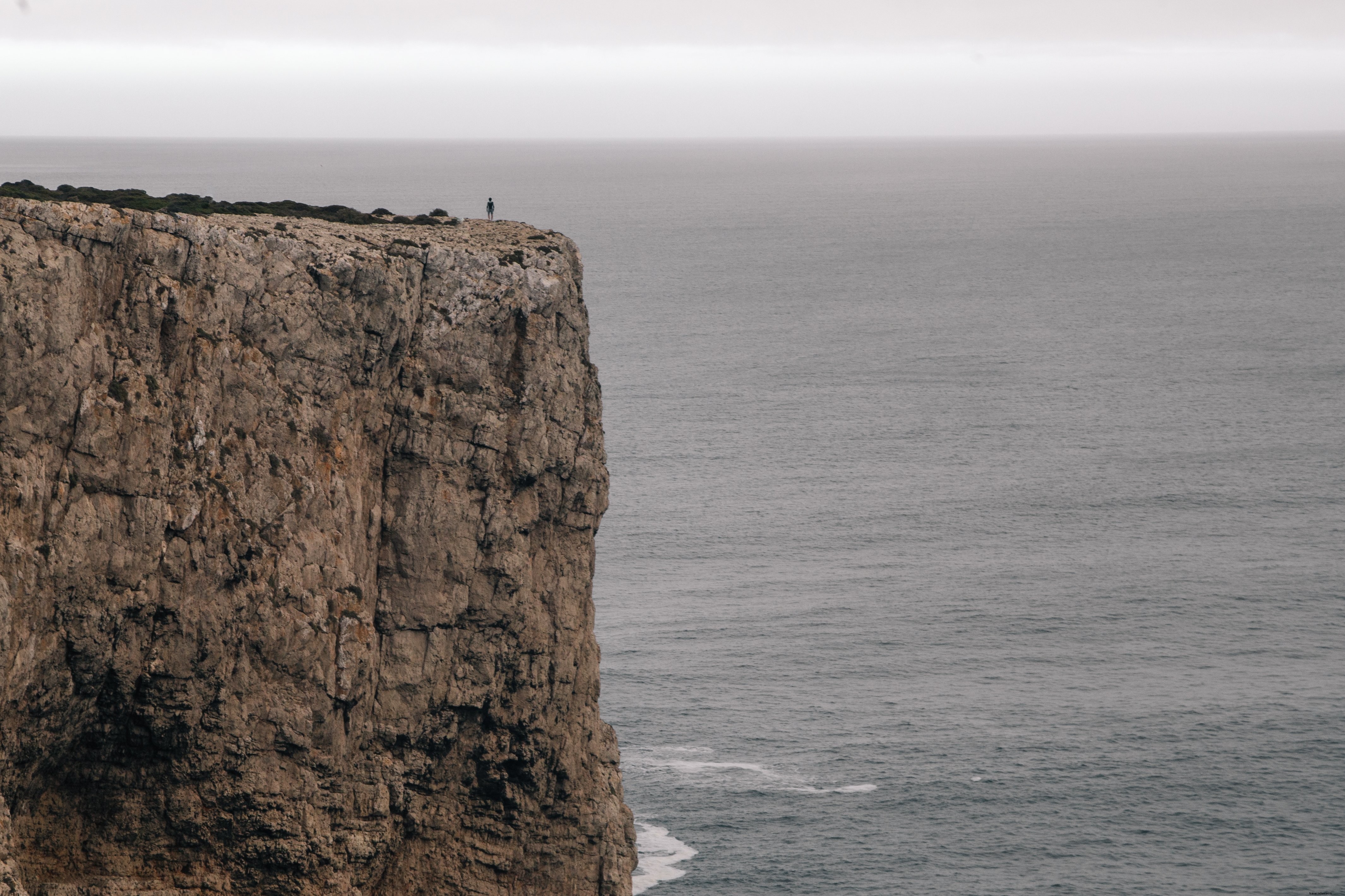 Figure sur une falaise dominant l océan sous un ciel gris