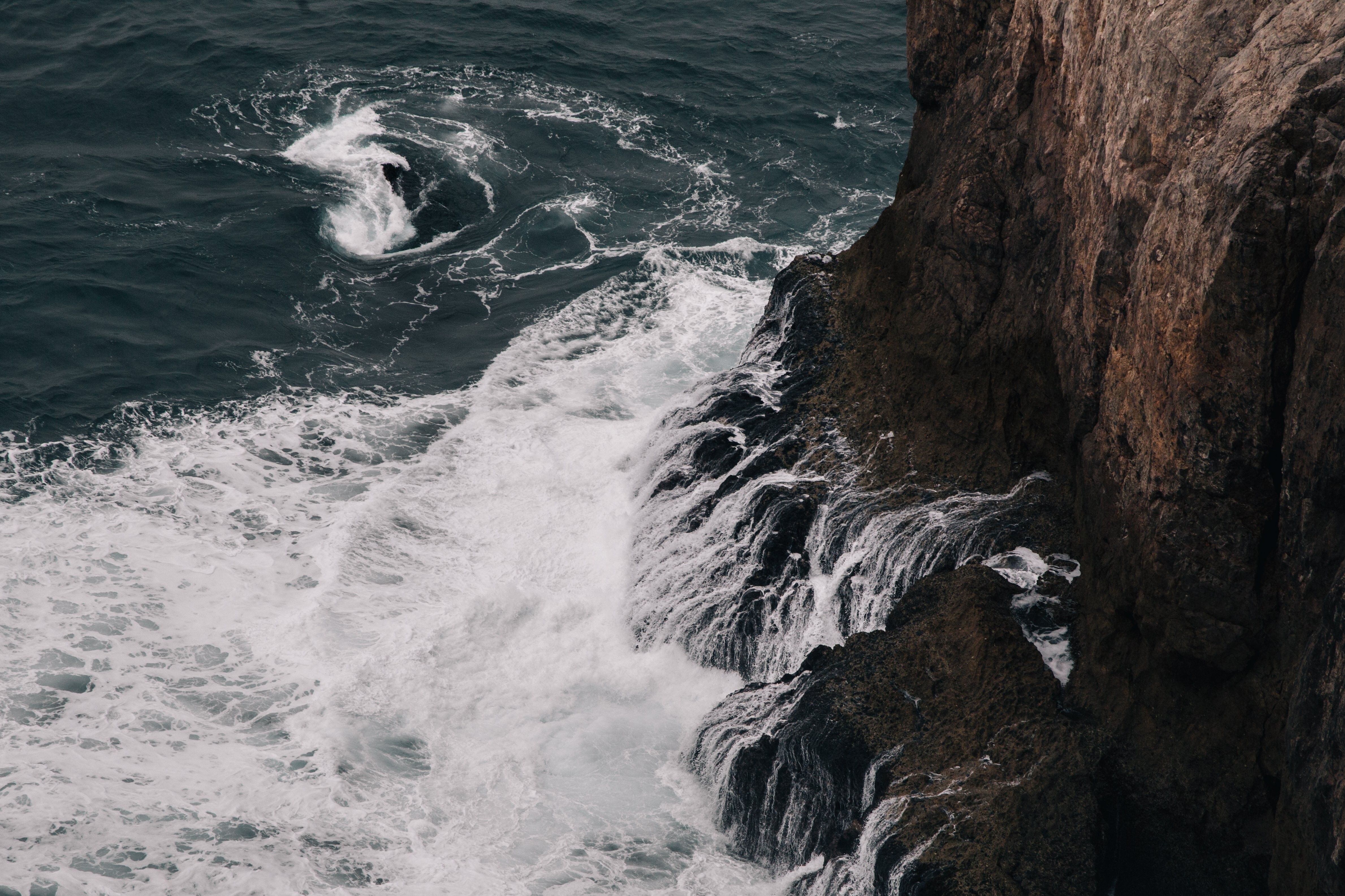 Griffes de vagues mousseuses au pied d’une falaise