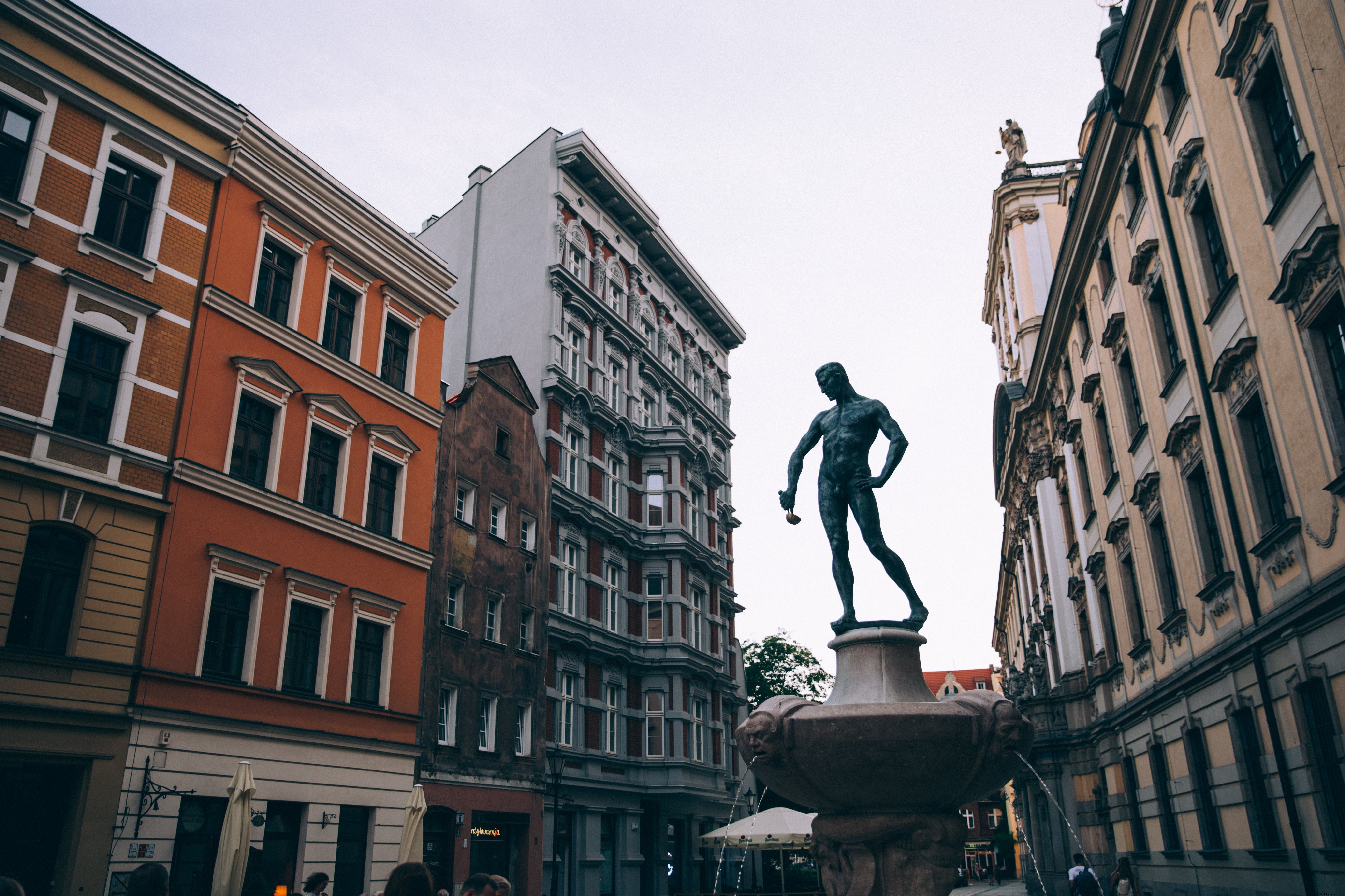 Statue d’un homme tenant une louche sur une place de ville