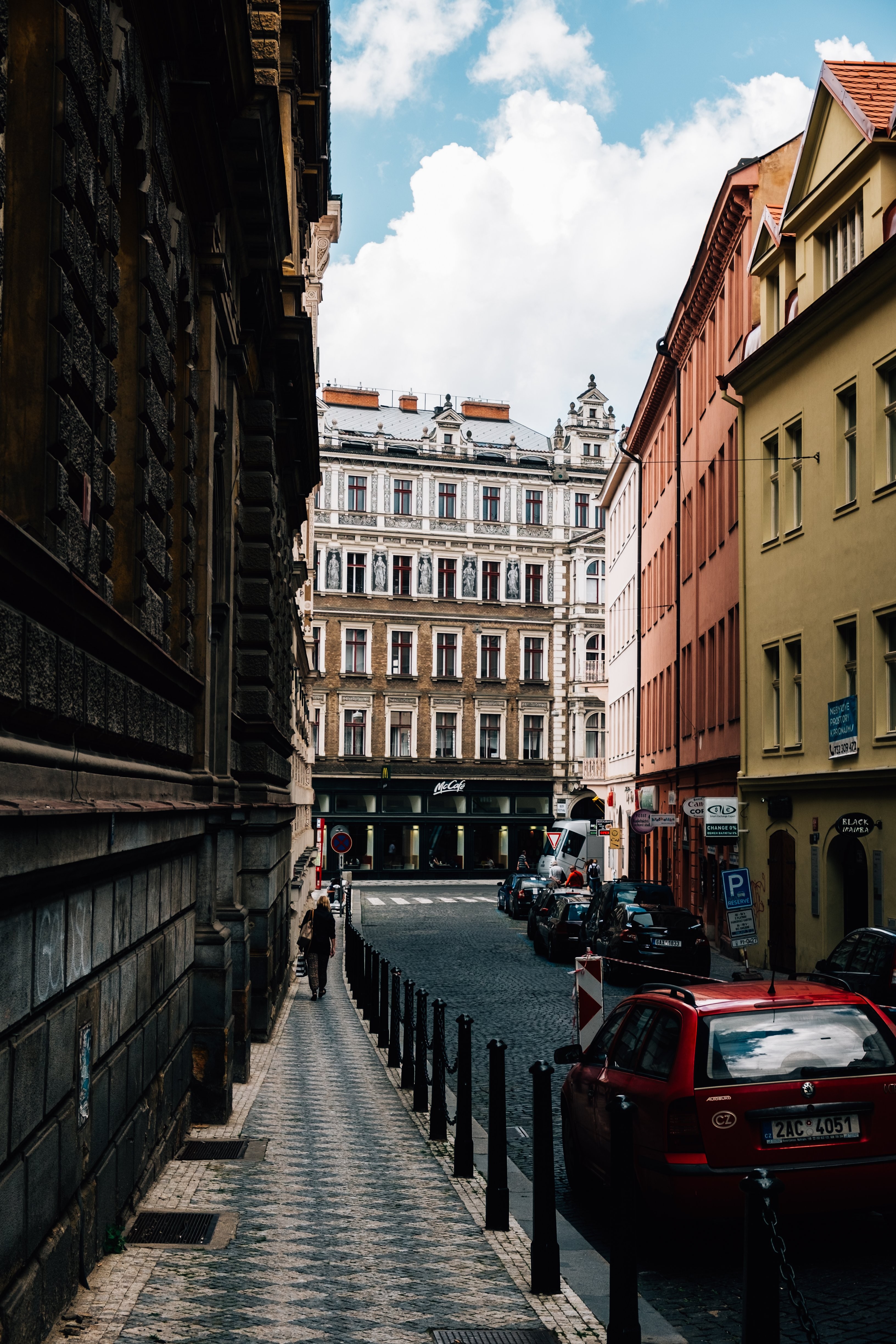De grands immeubles bordent une rue étroite où des voitures sont stationnées