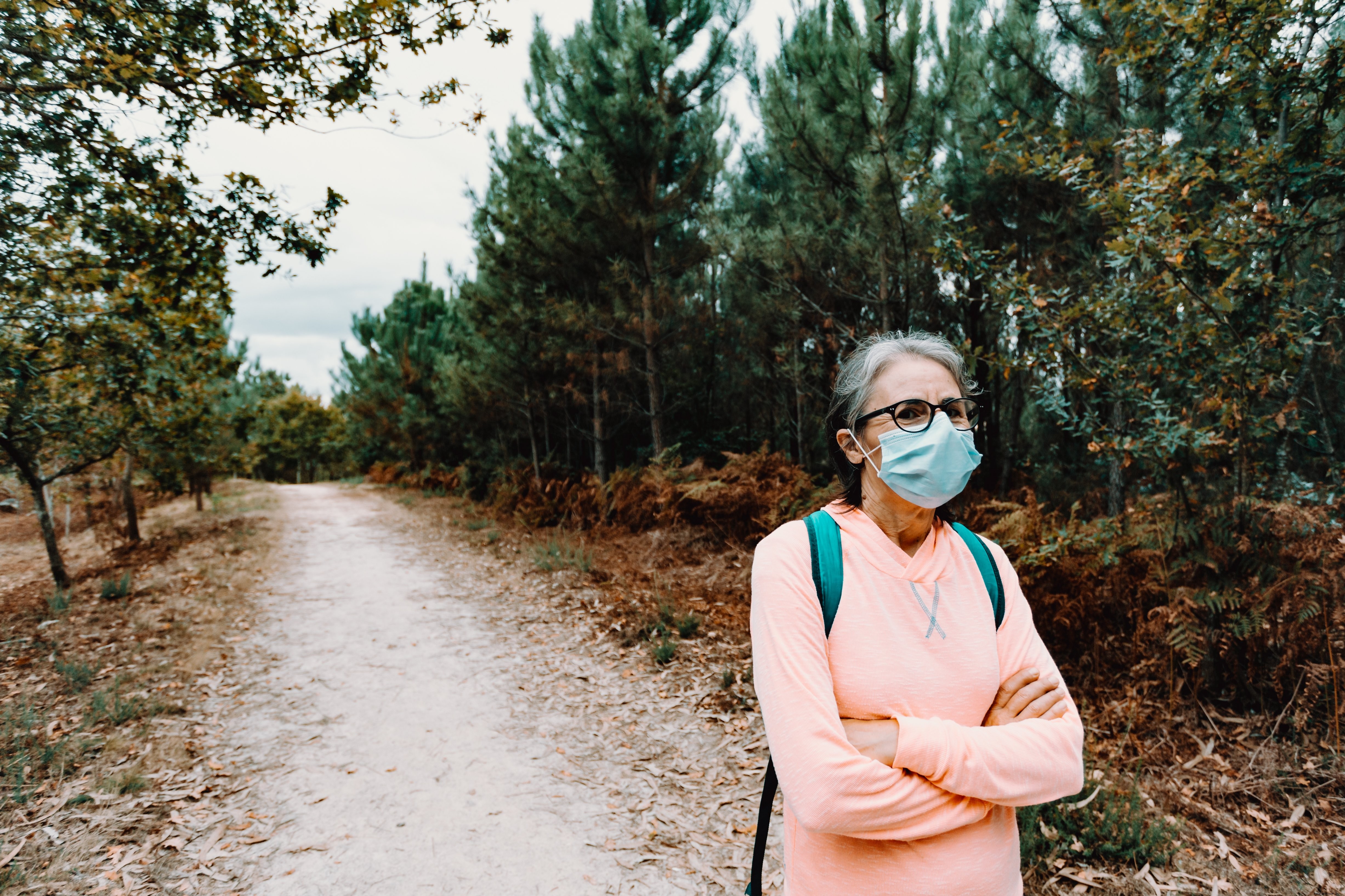 Femme masquée se tient sur un sentier de randonnée