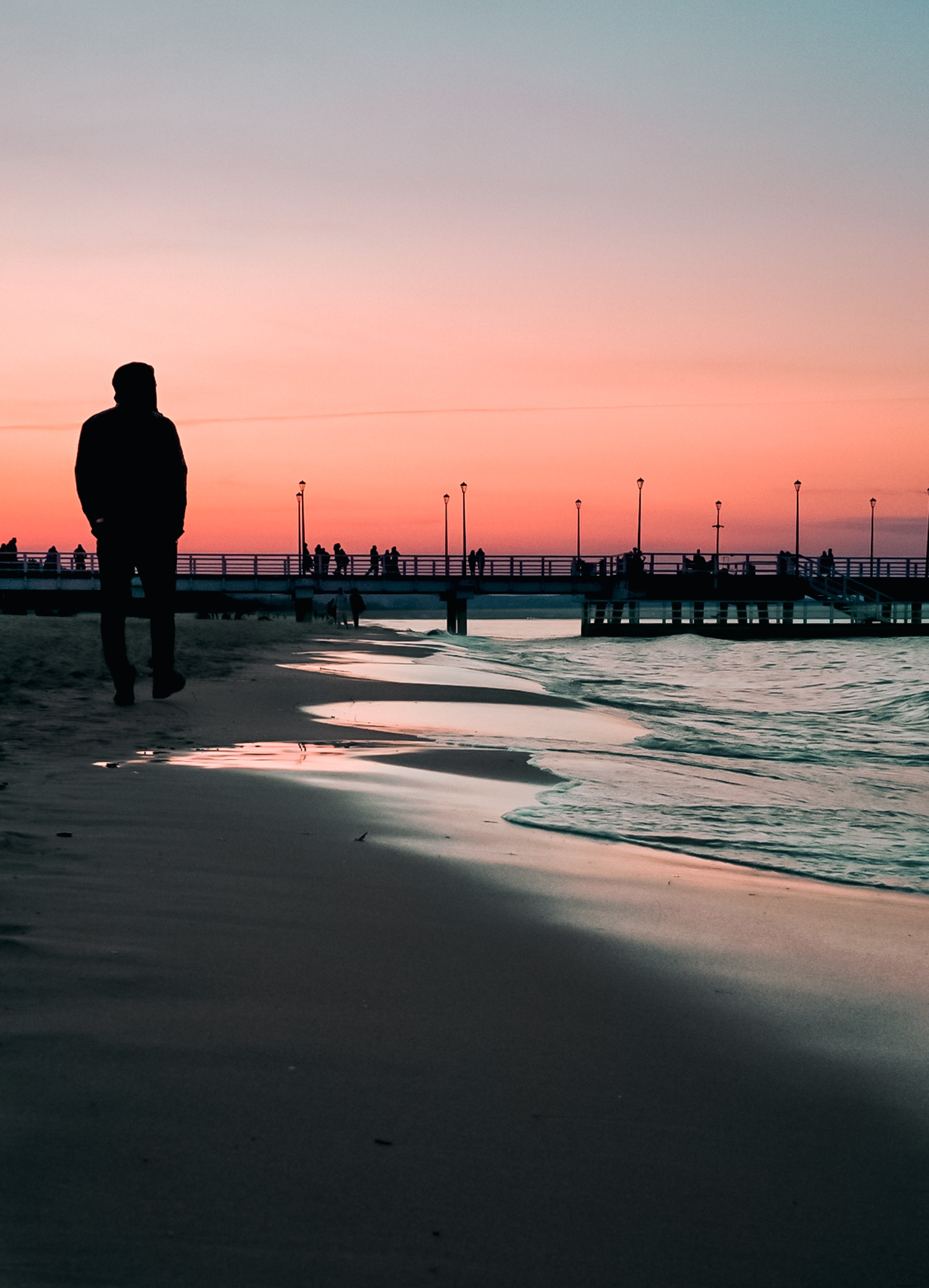 Balade sur la plage au coucher du soleil, jetée au loin