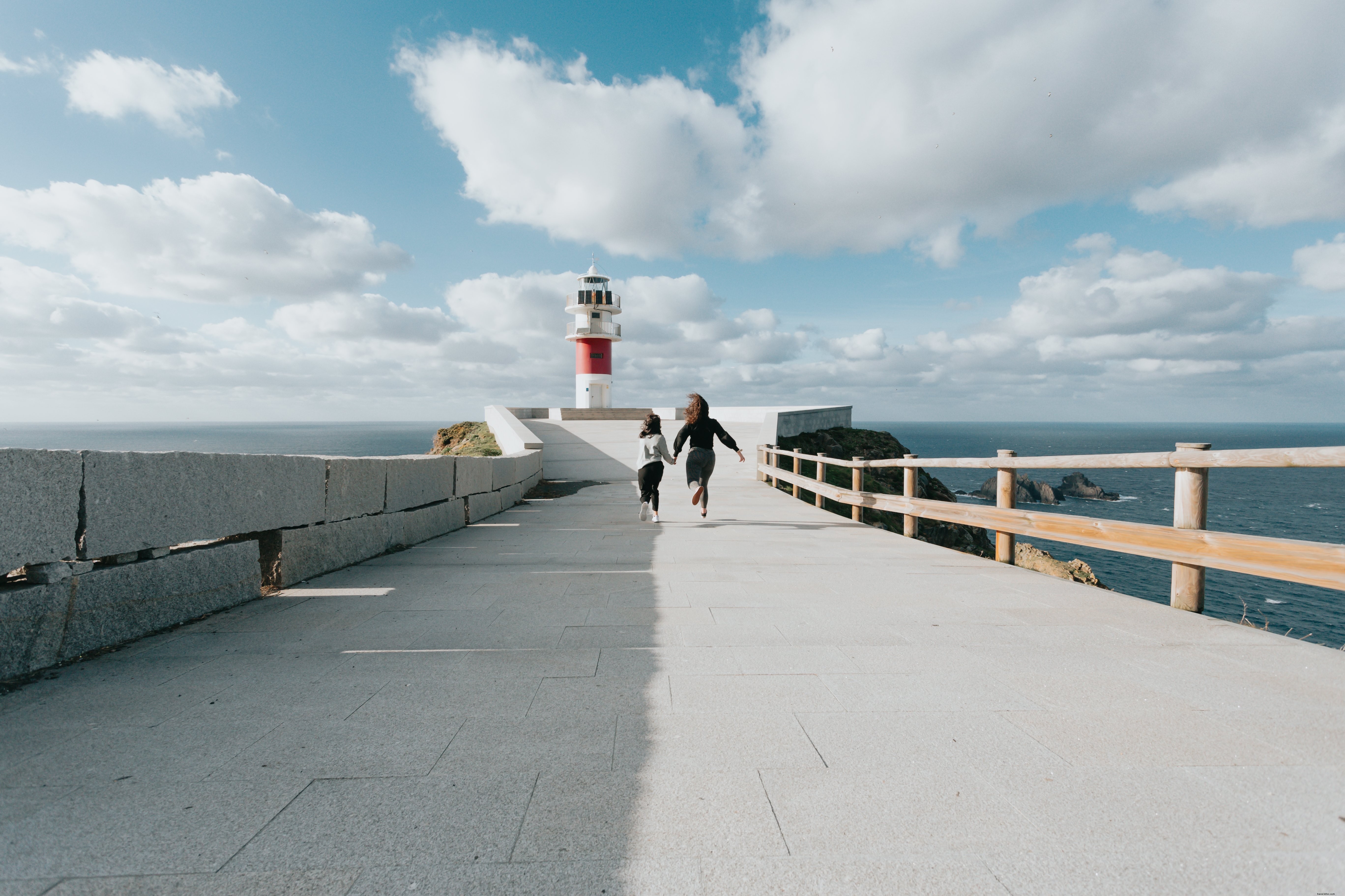 Deux personnes courent sur une route pavée en direction d’un phare