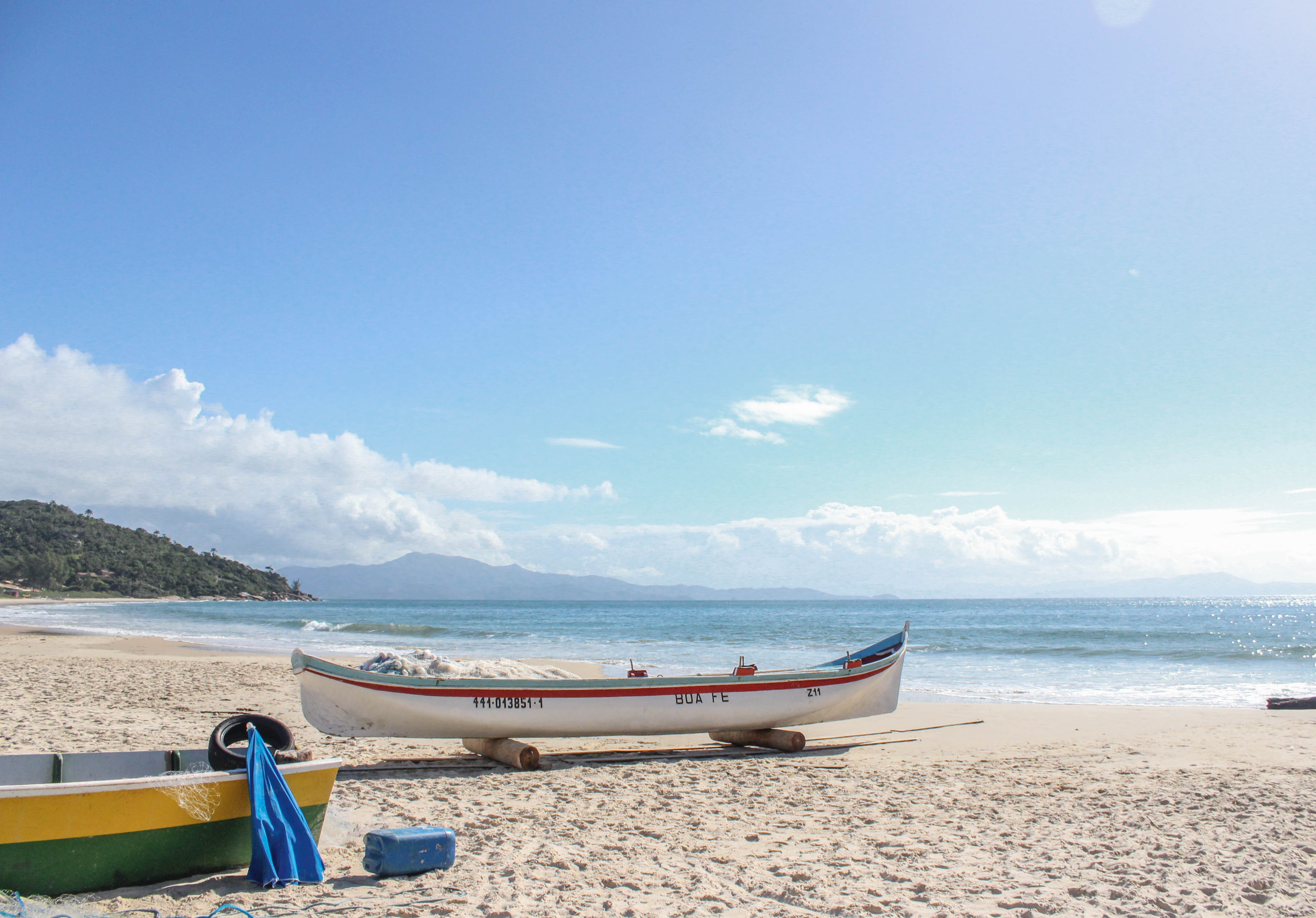 Un bateau blanc à bande rouge sur une plage de sable