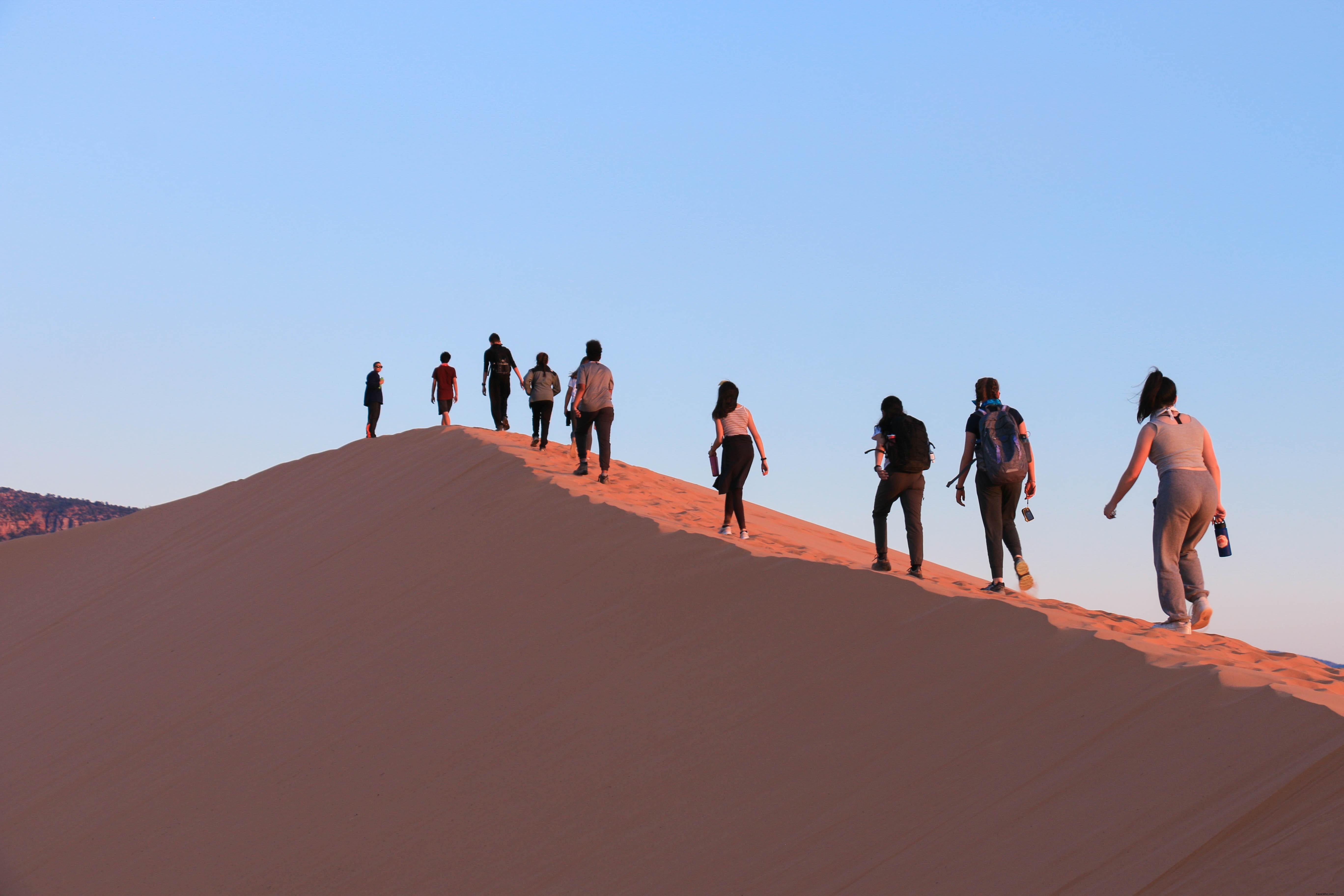 Des touristes escaladent des dunes de sable abruptes