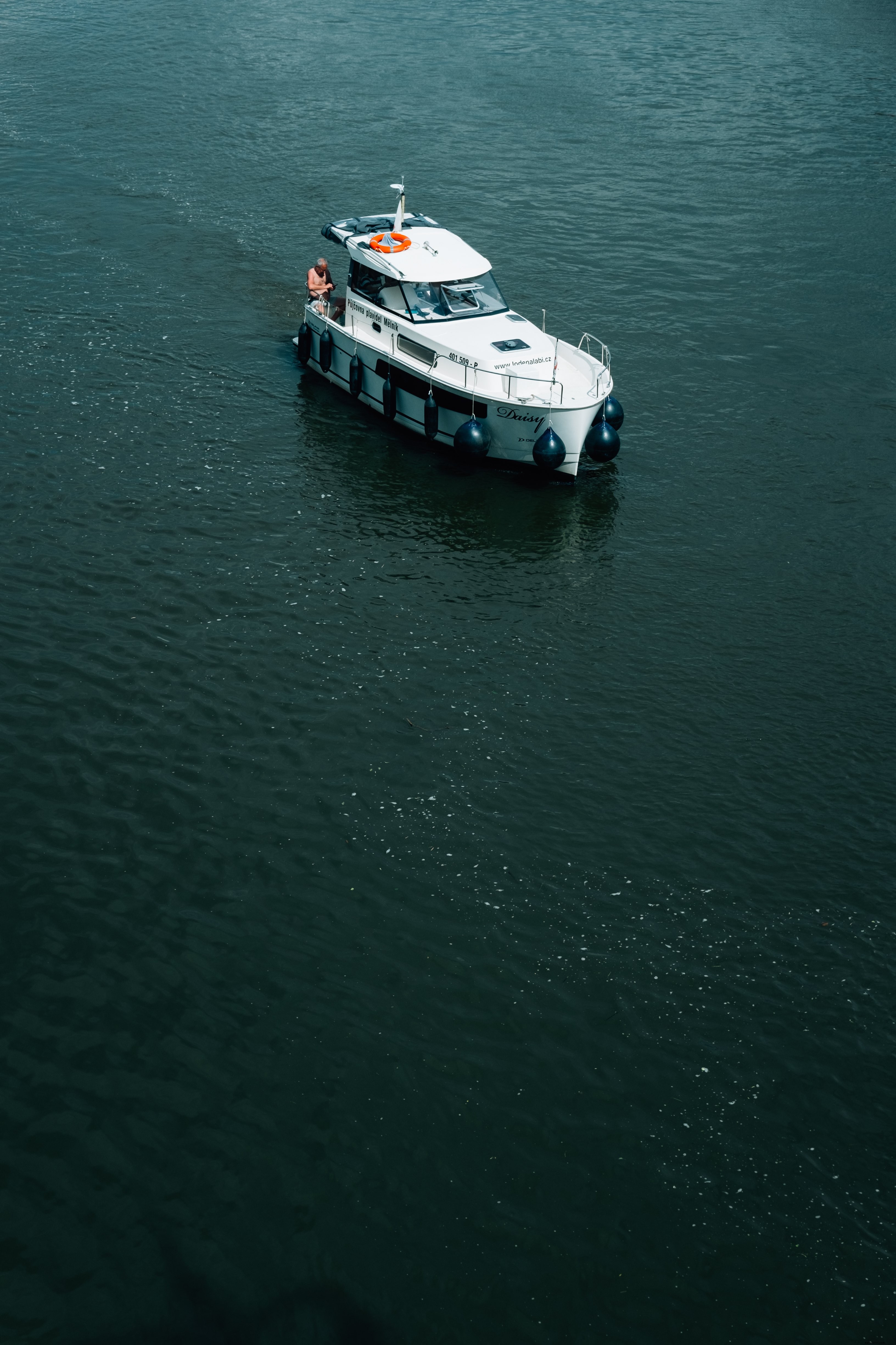 Photo d un bateau blanc avec une personne dans une eau bleu foncé