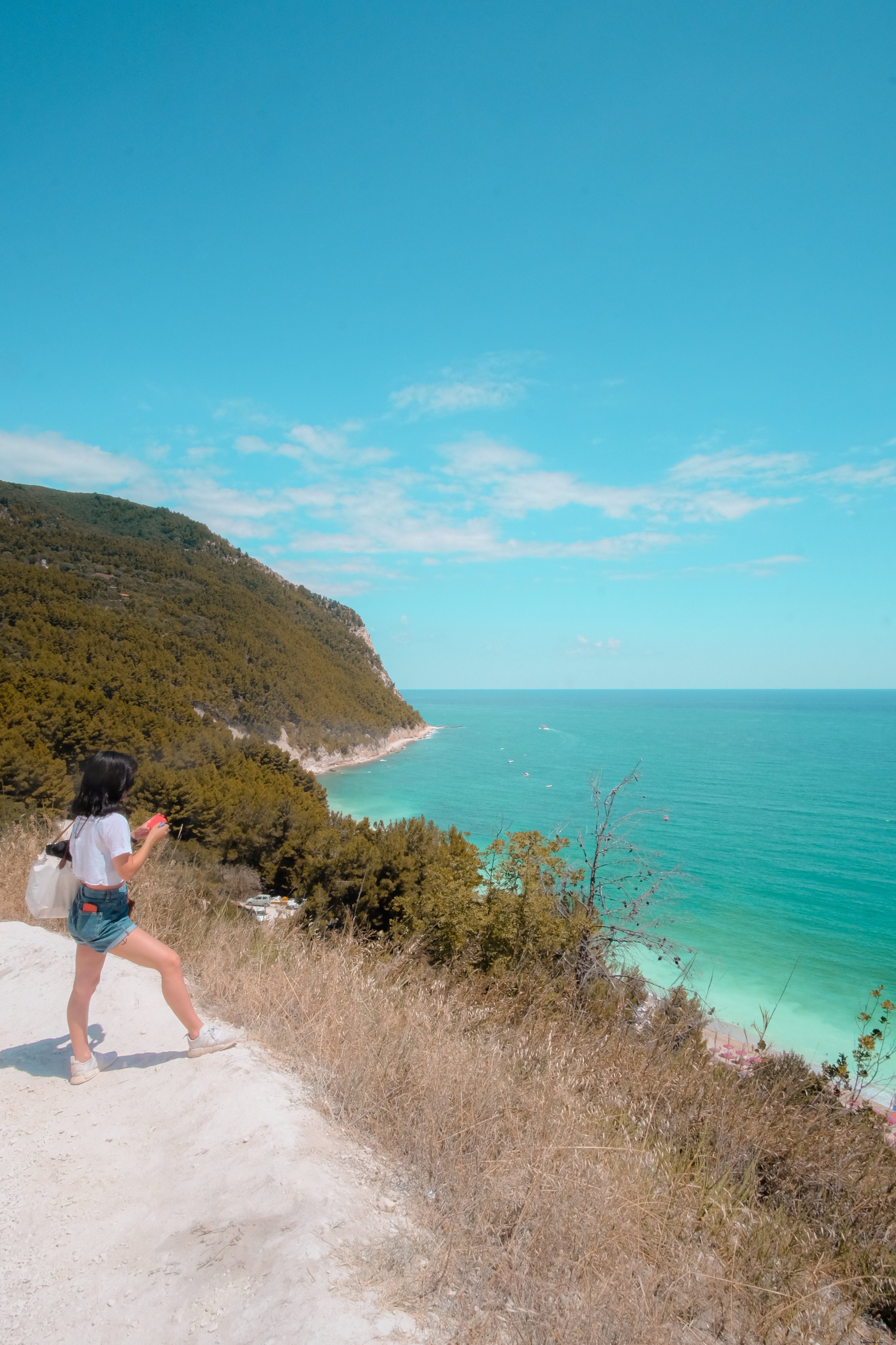 Une personne debout sur une colline de sable blanc, face à l océan