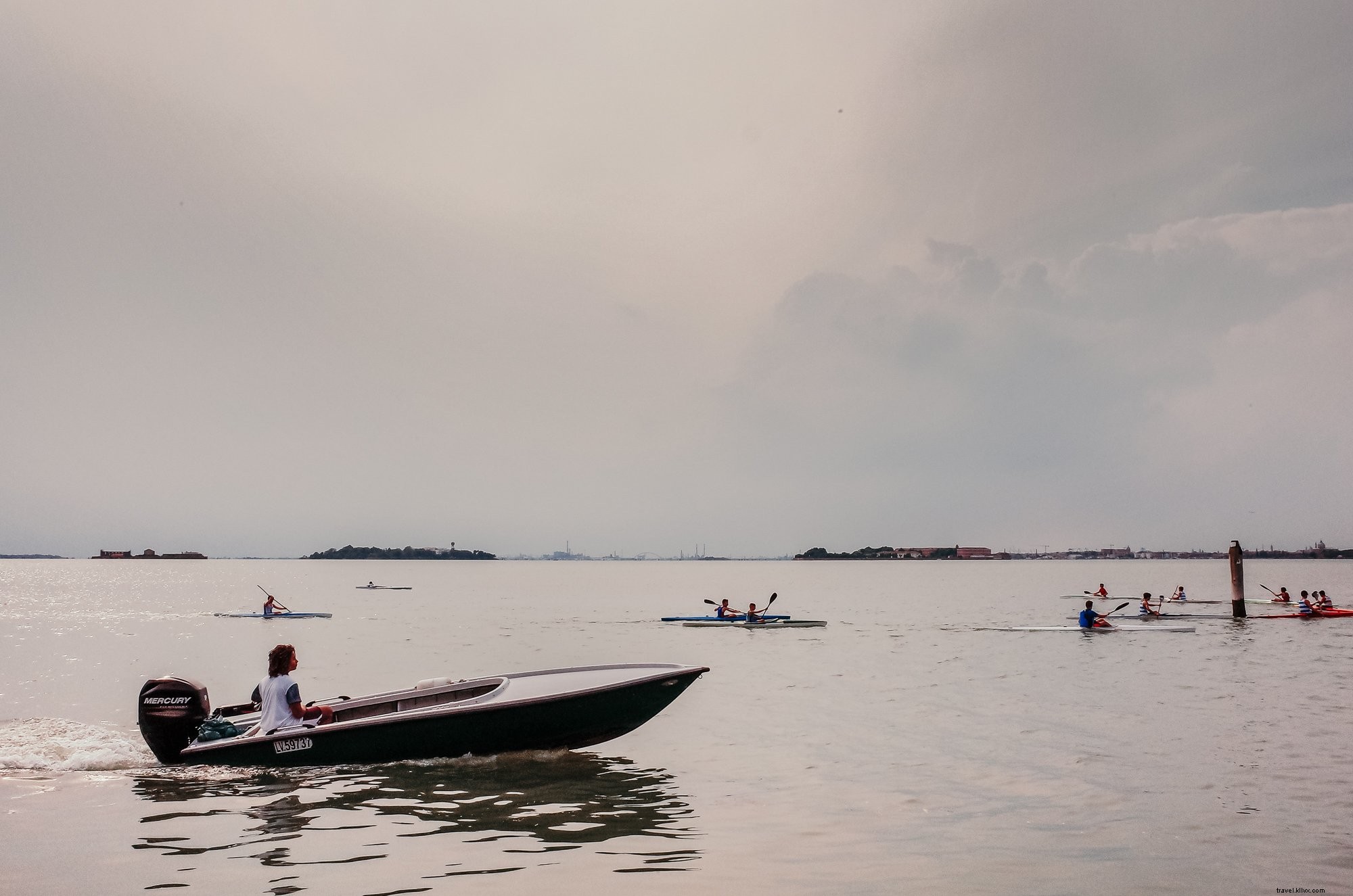 Des kayakistes sous un ciel nuageux, un bateau à l arrière