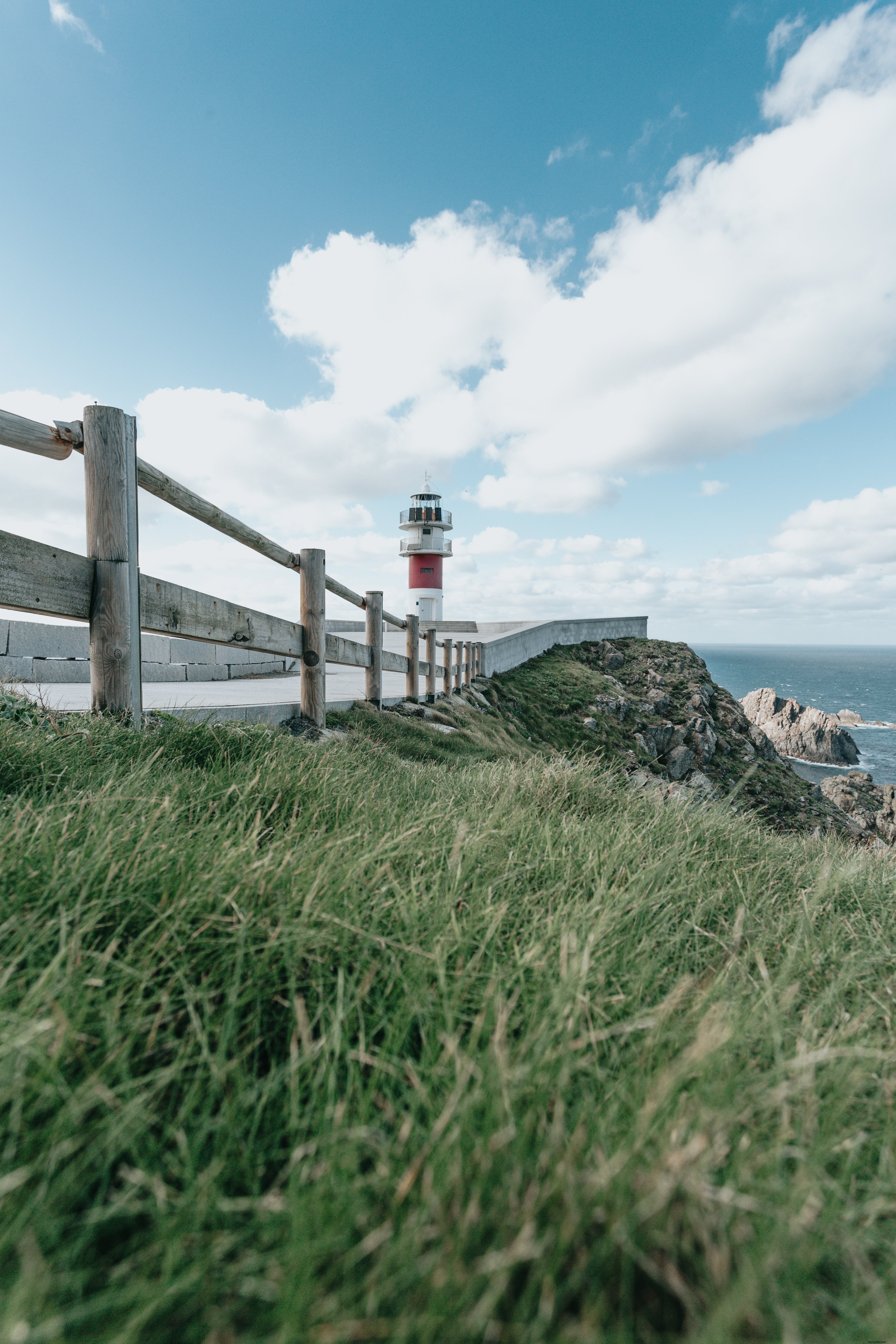 Herbe verte, clôture en bois et phare en arrière-plan
