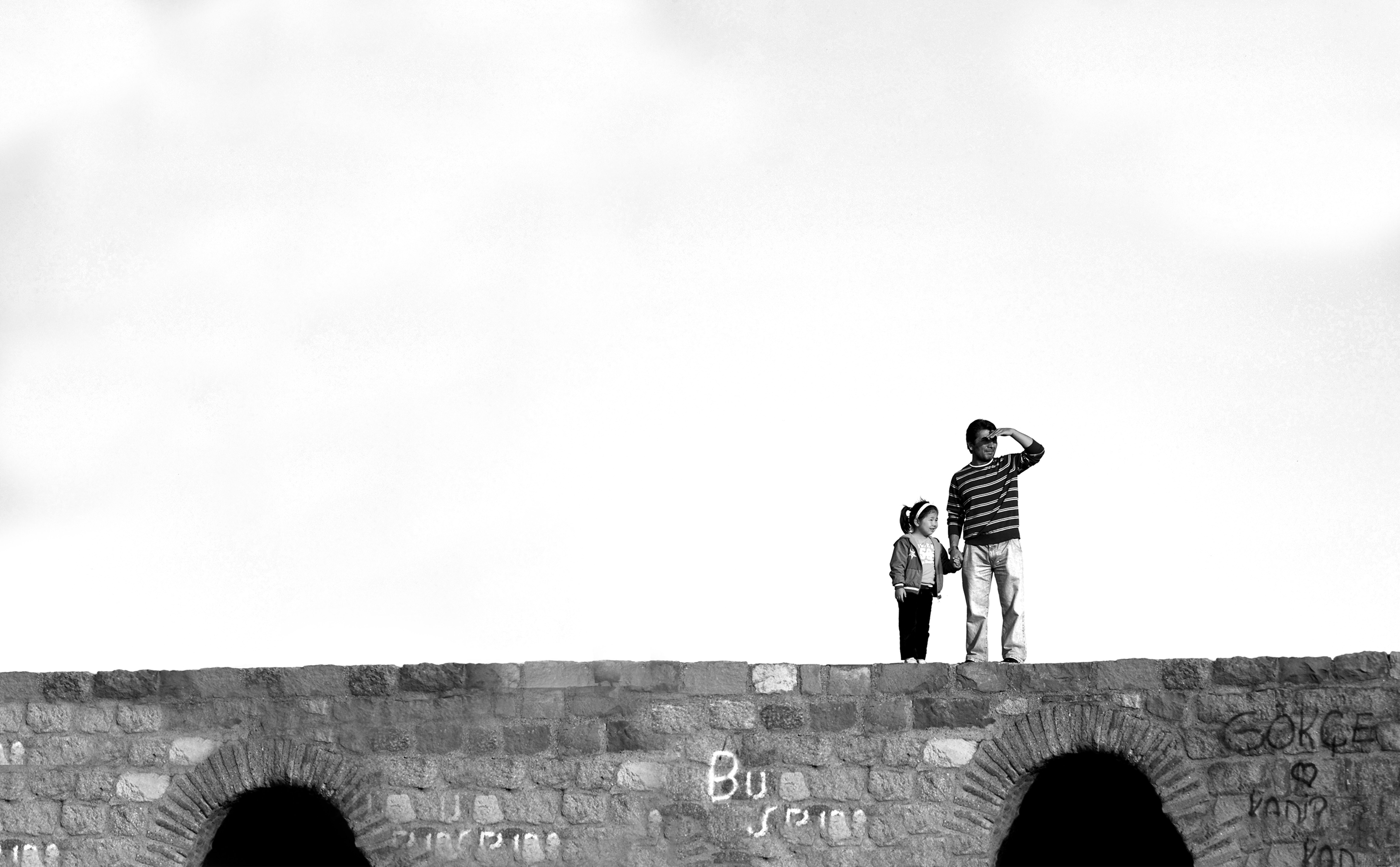 Photo en noir et blanc de deux personnes sur un pont de pierre