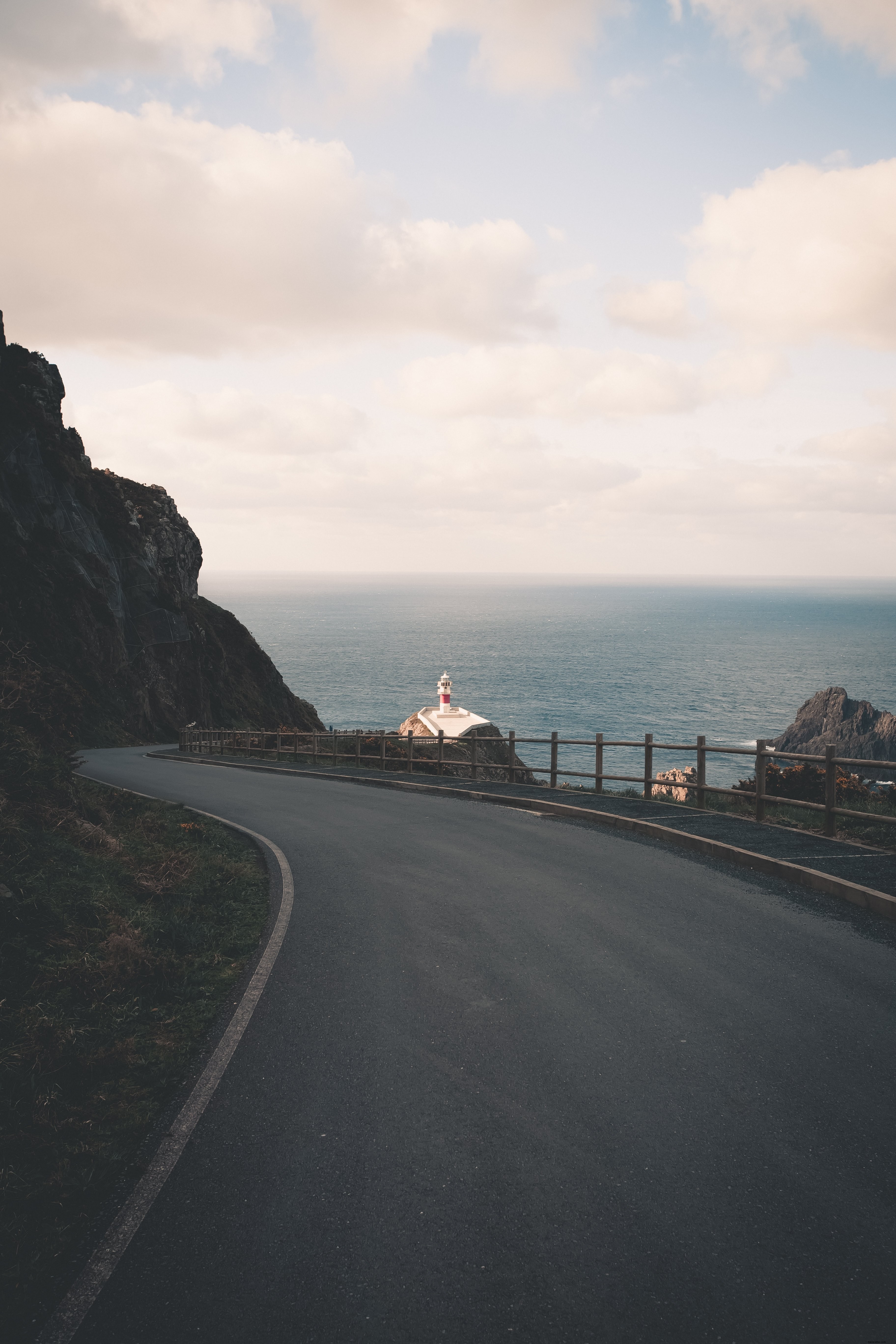 Photo d une route pavée sinueuse avec un phare au loin