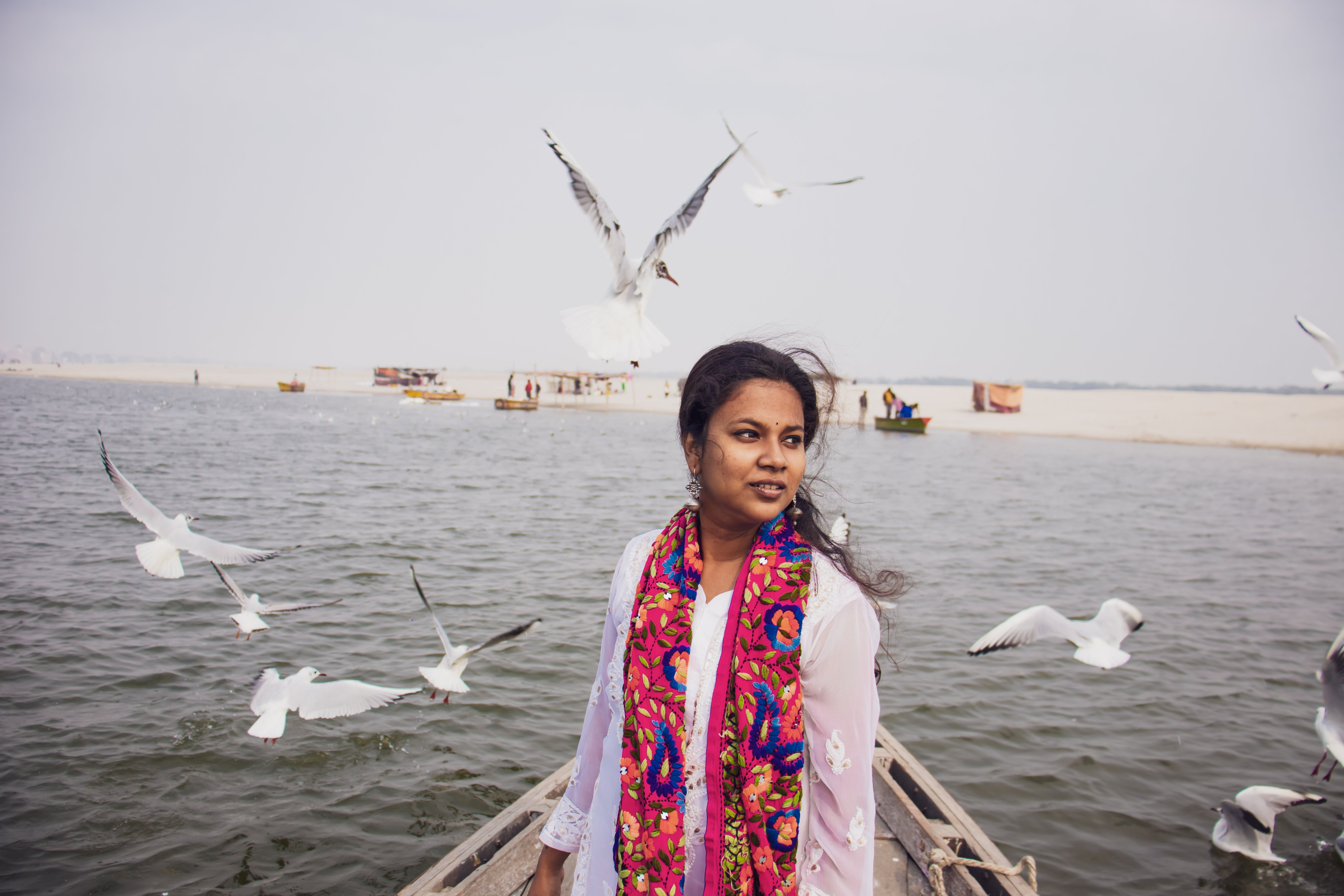 Une personne debout sur un bateau, entourée d’oiseaux – Photo