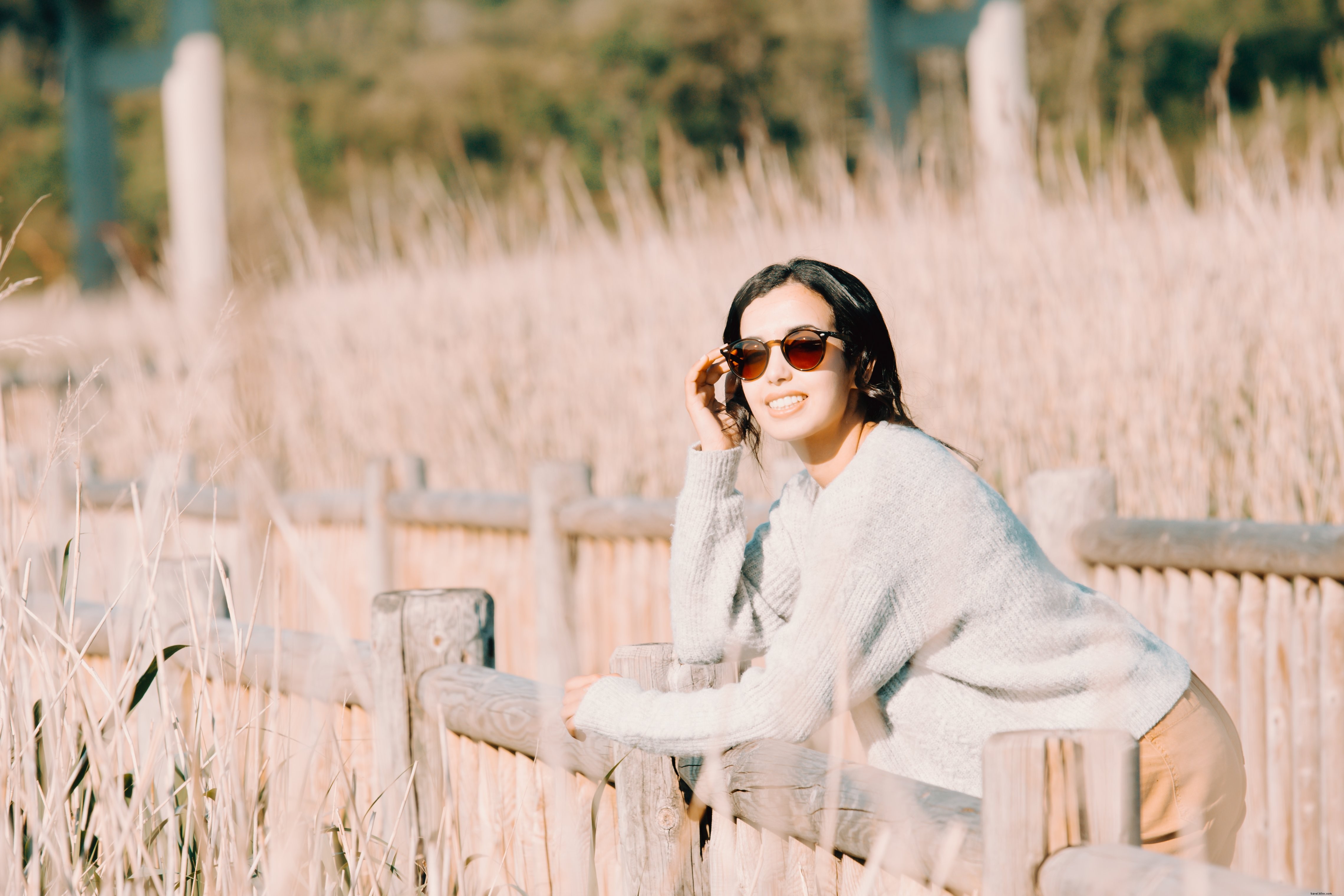 Photo d une femme portant des lunettes, appuyée contre une clôture en bois