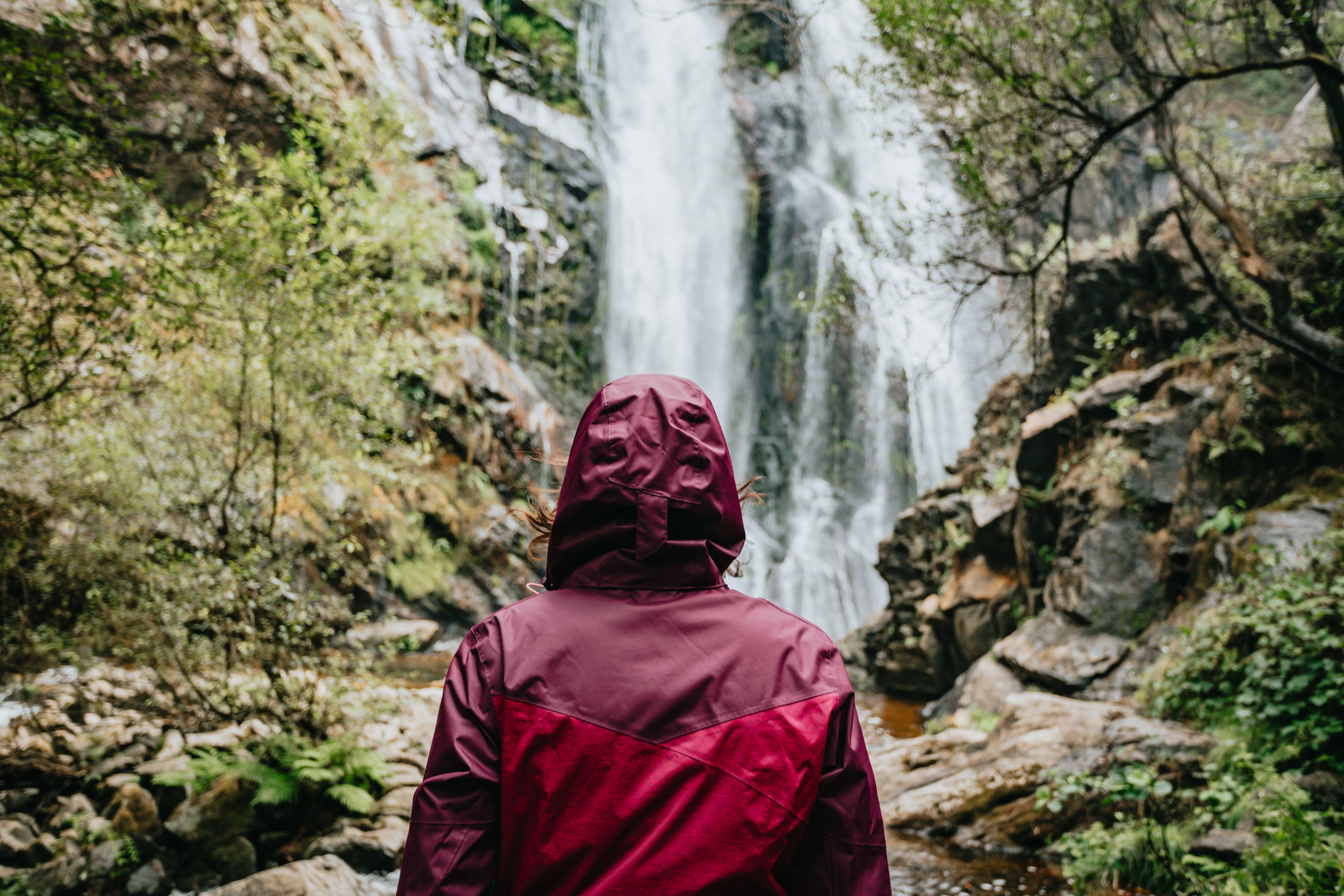 Une personne sous un imperméable évoque une grande cascade