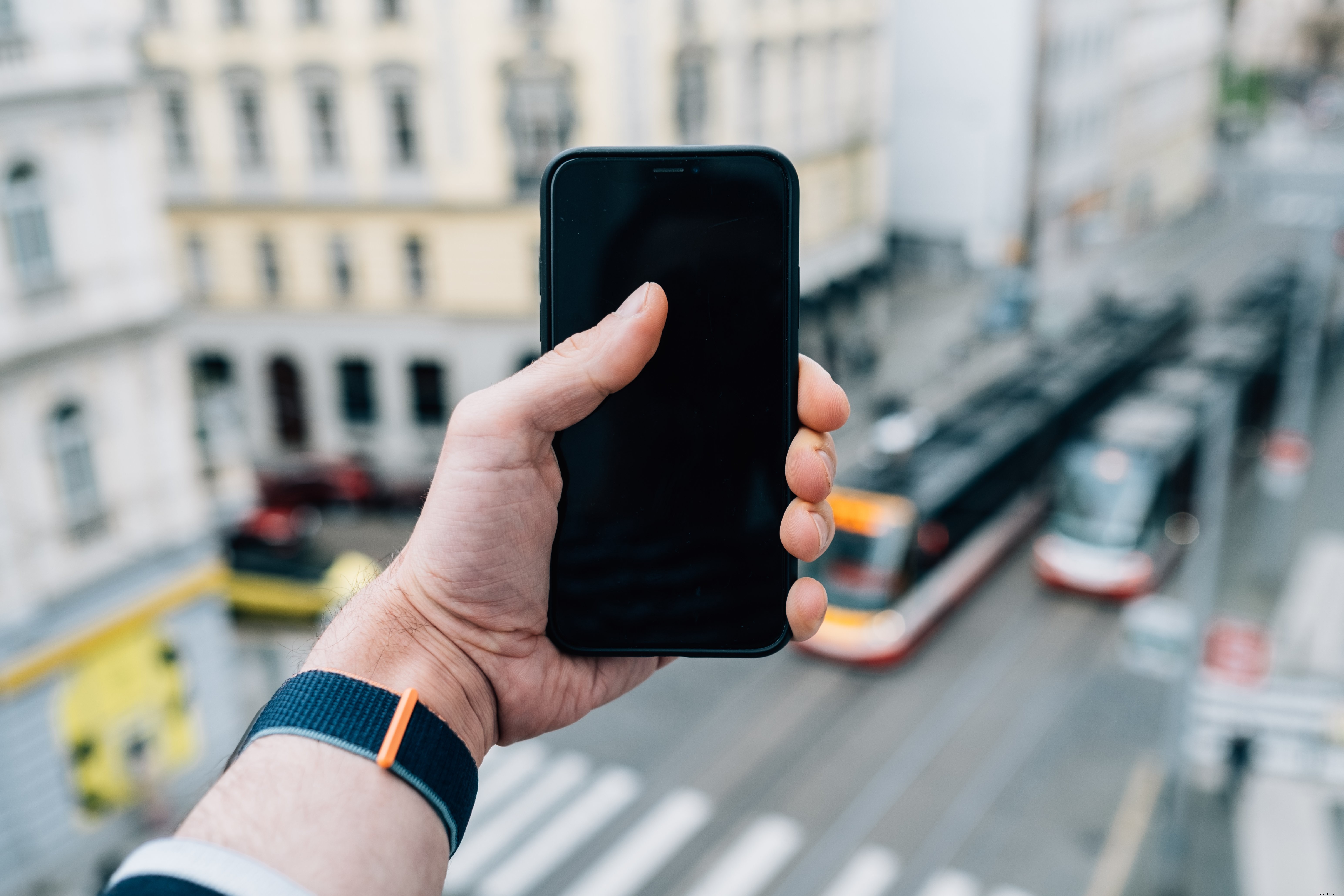 Main tend un smartphone noir devant un paysage flou