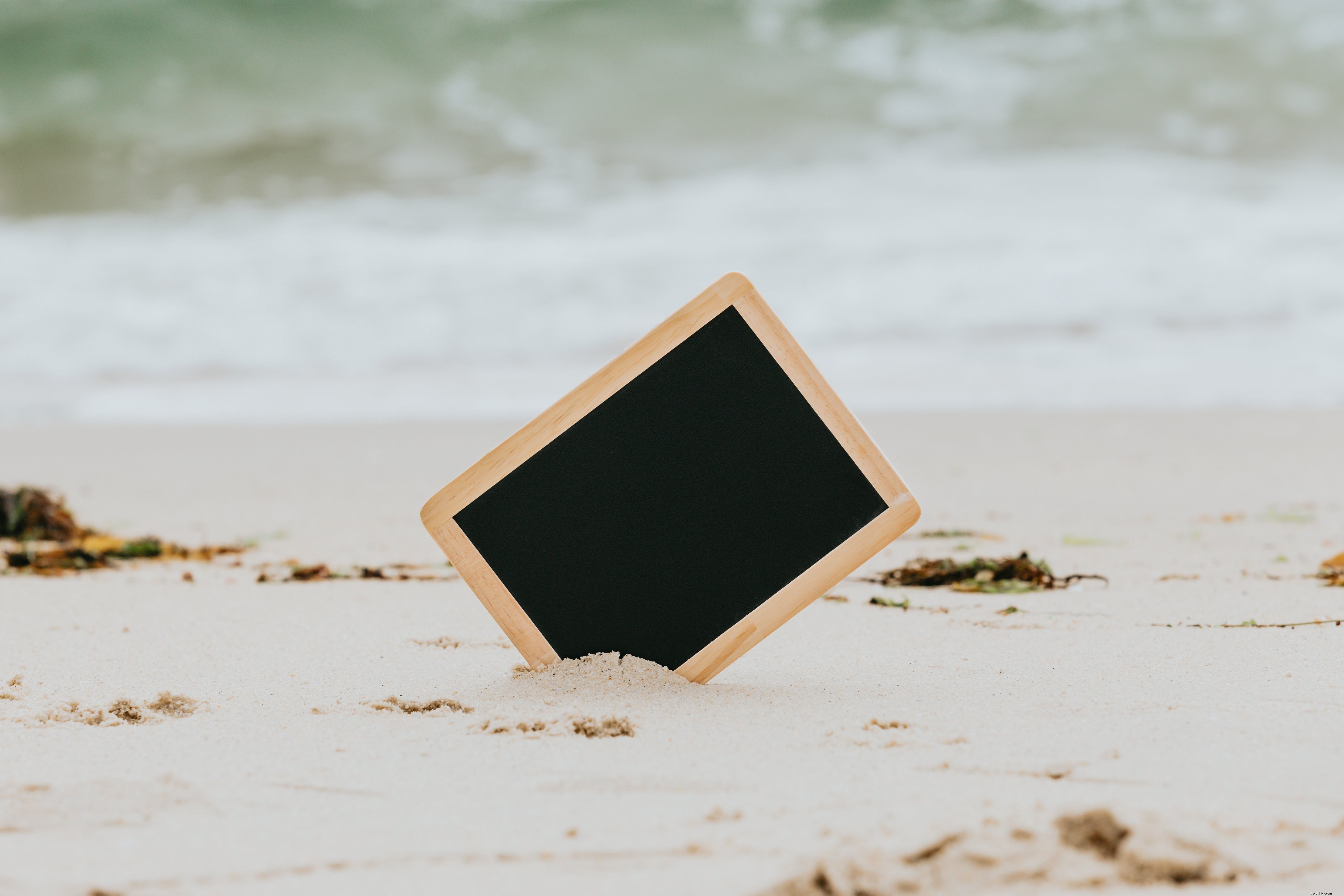 Tableau noir surgissant d’une plage de sable blanc