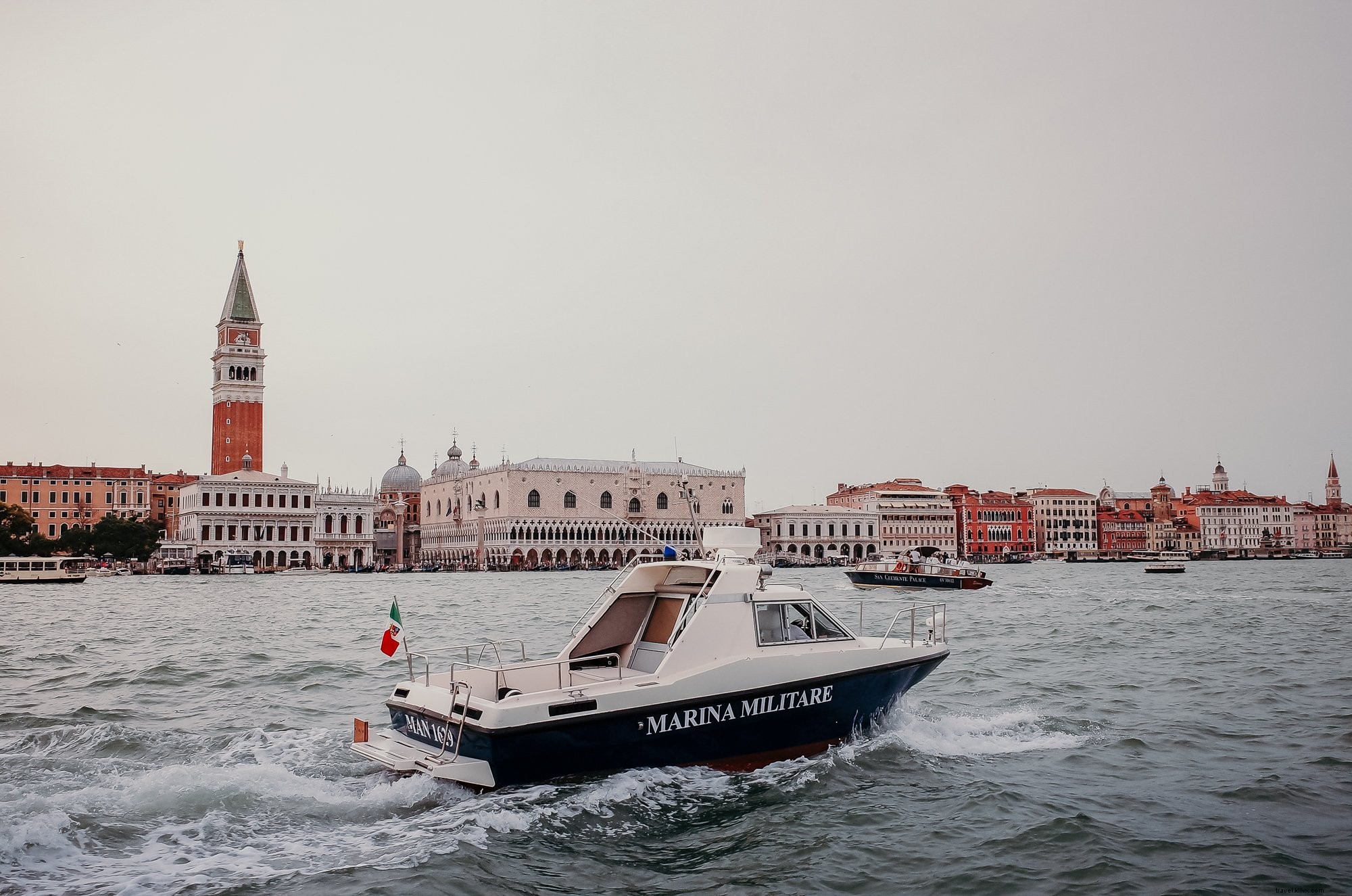 Bateau naviguant sur des eaux ondulées avec des bâtiments à l horizon – Photo