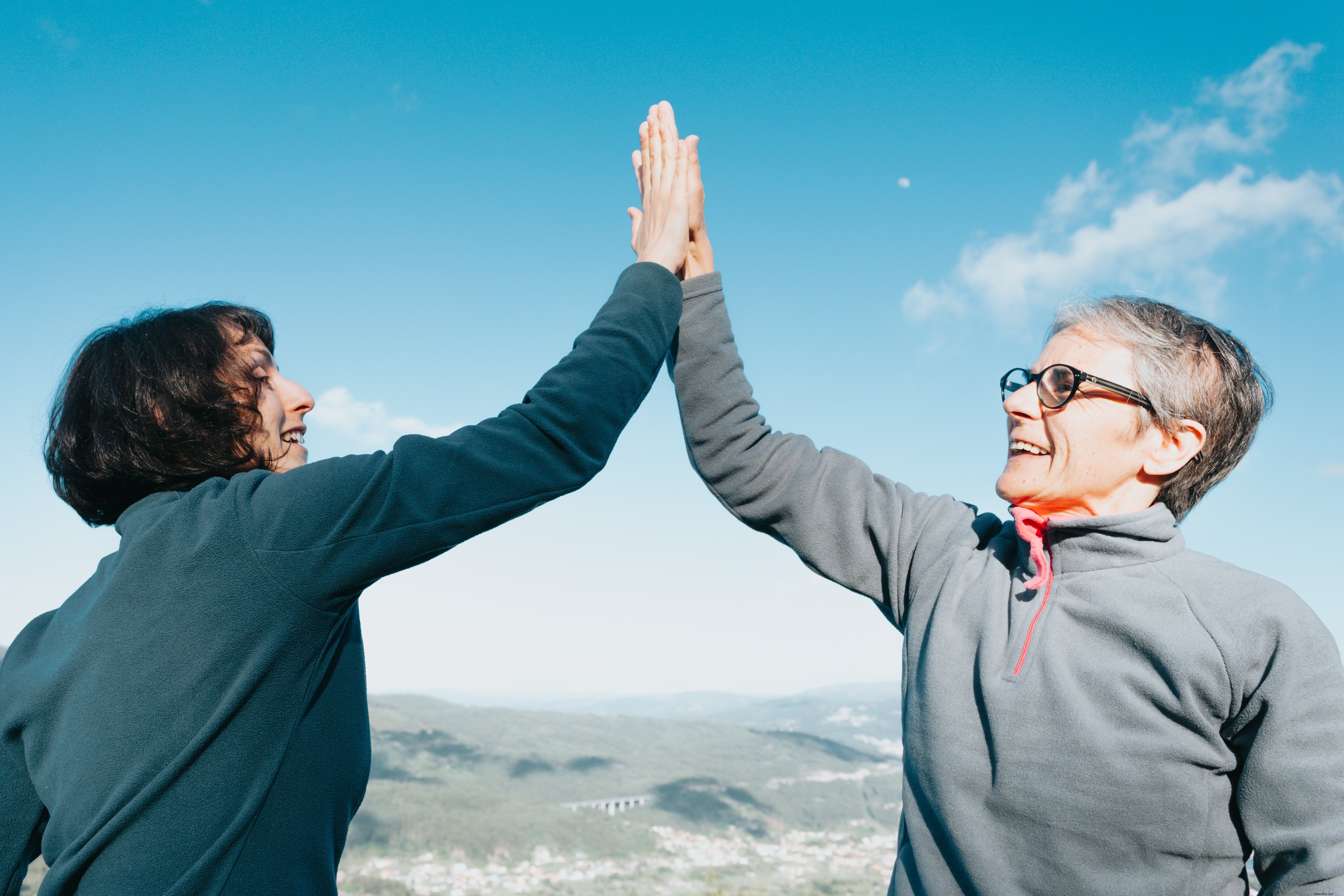 Deux femmes se donnent un high‑five sous un ciel bleu éclatant