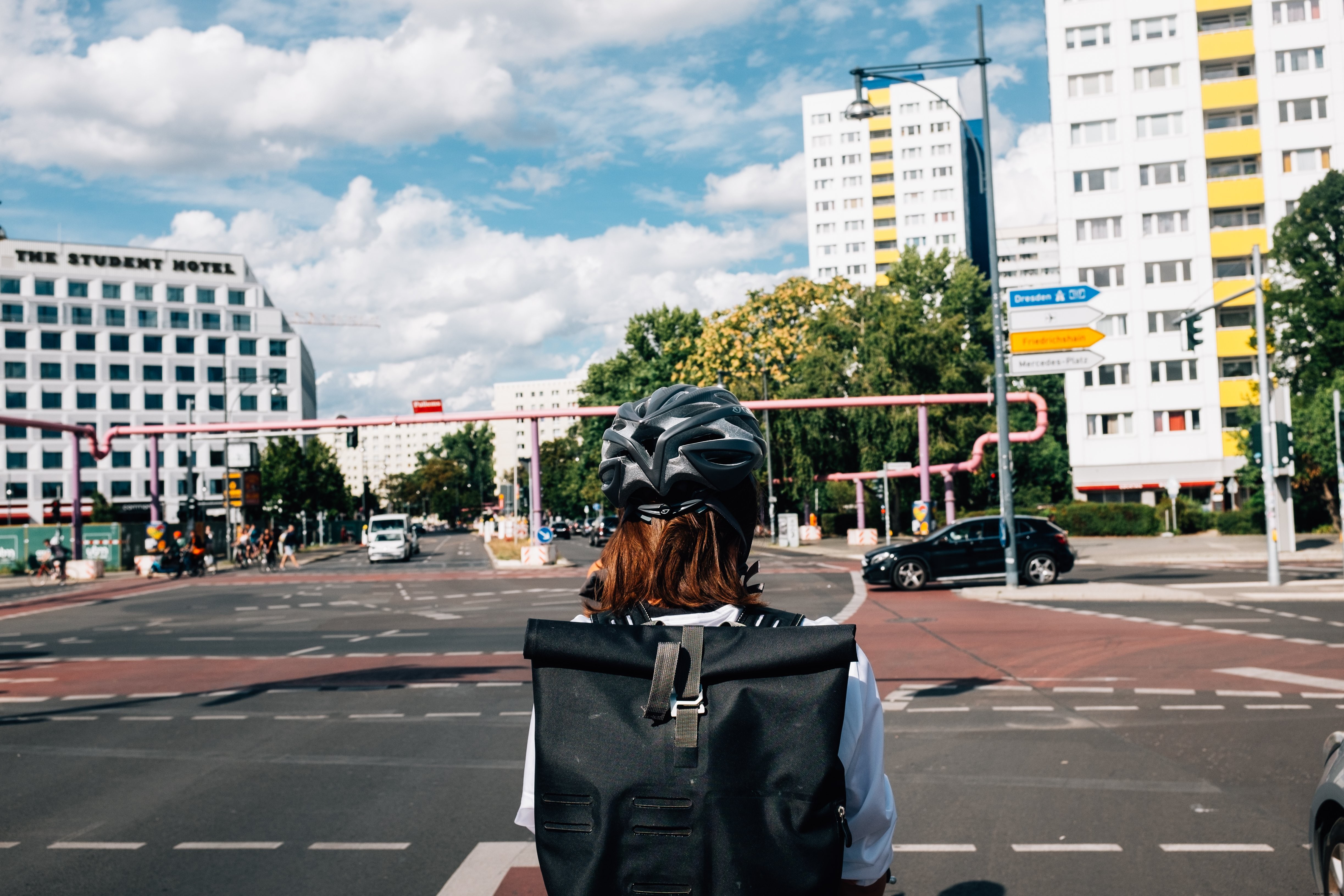 Un piéton au casque noir attend son tour à un carrefour animé