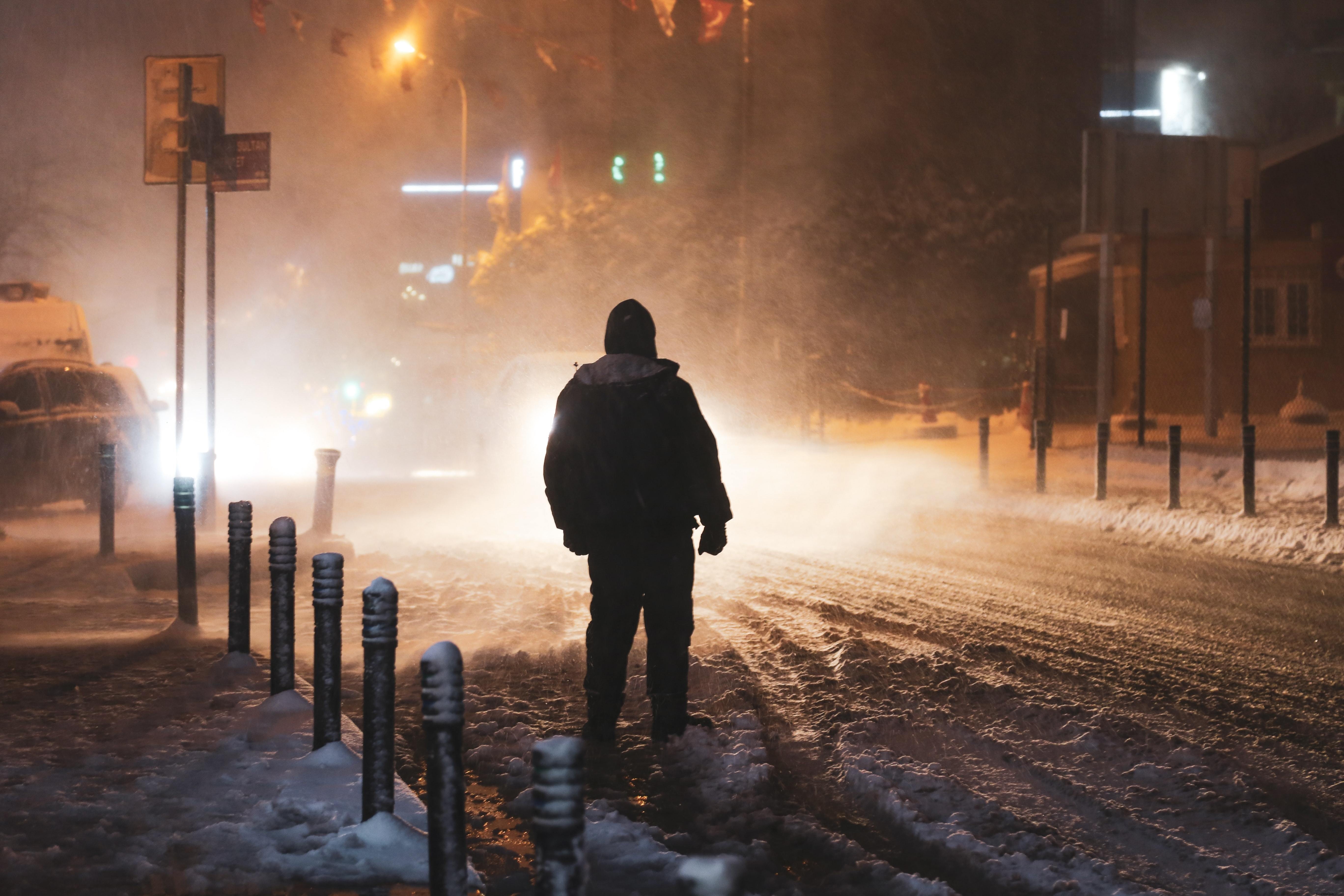 Personne illuminée par les lampadaires pendant une tempête de neige